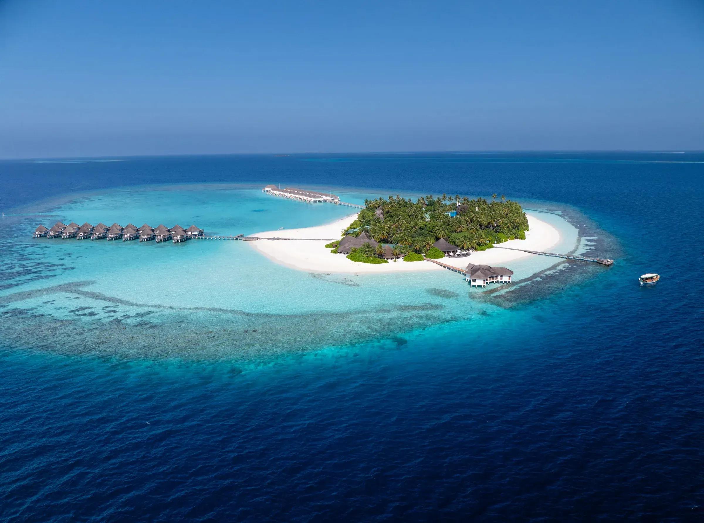Veduta aerea dell'Angaga Island Resort & Spa con bungalow sull'acqua e spiaggia bianca.