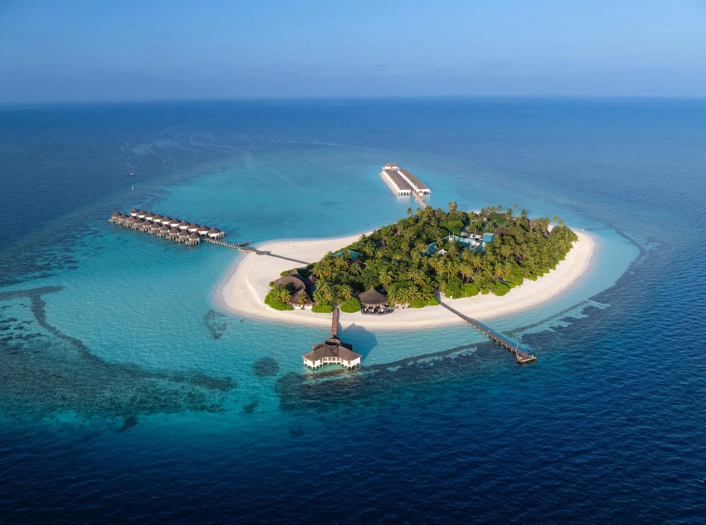 Vista aerea di Angaga Island Resort & Spa con bungalow su palafitte e spiaggia bianca.