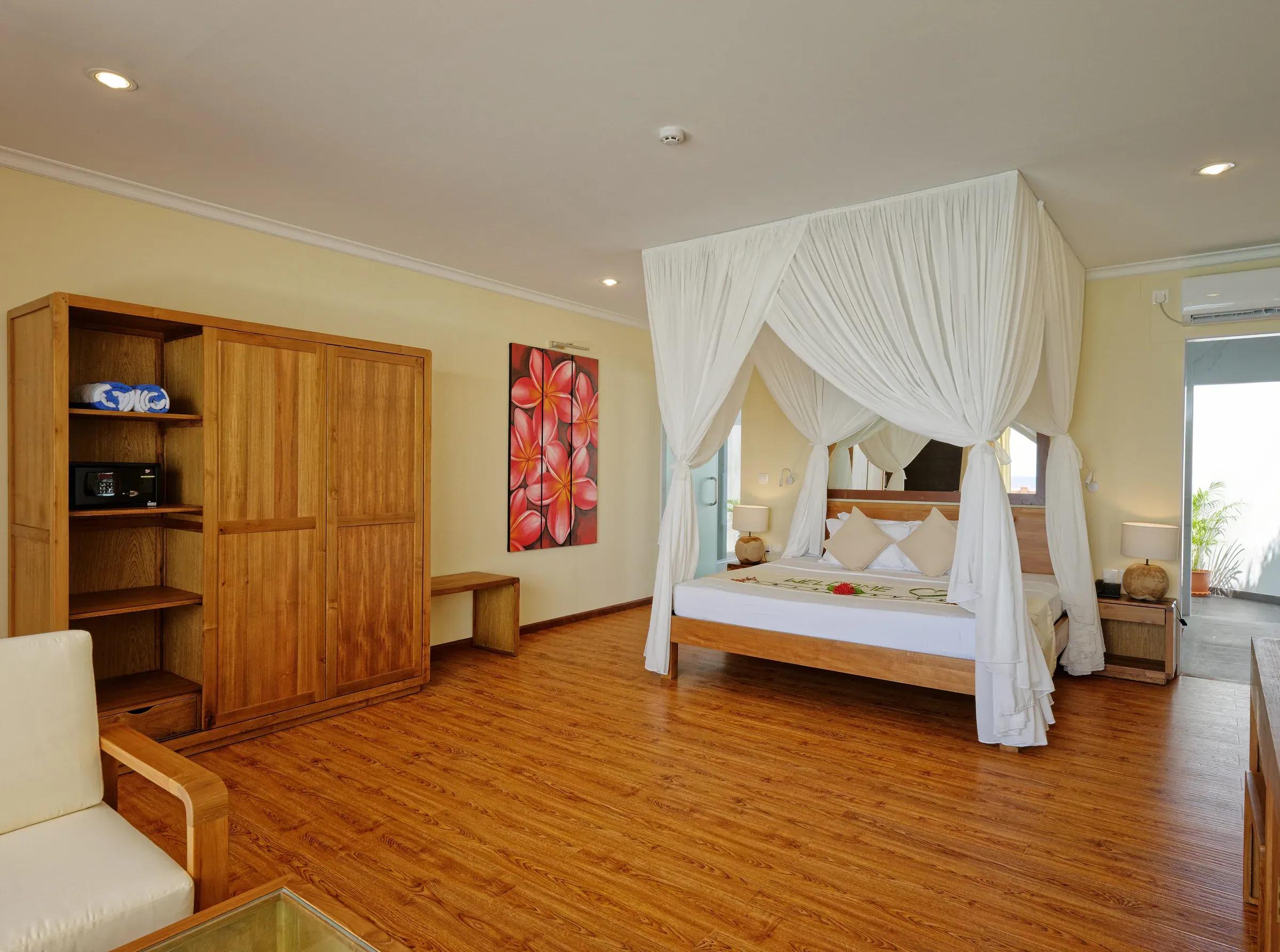 Camera della Premium Water Bungalow con letto a baldacchino e armadio al Angaga Island Resort & Spa.