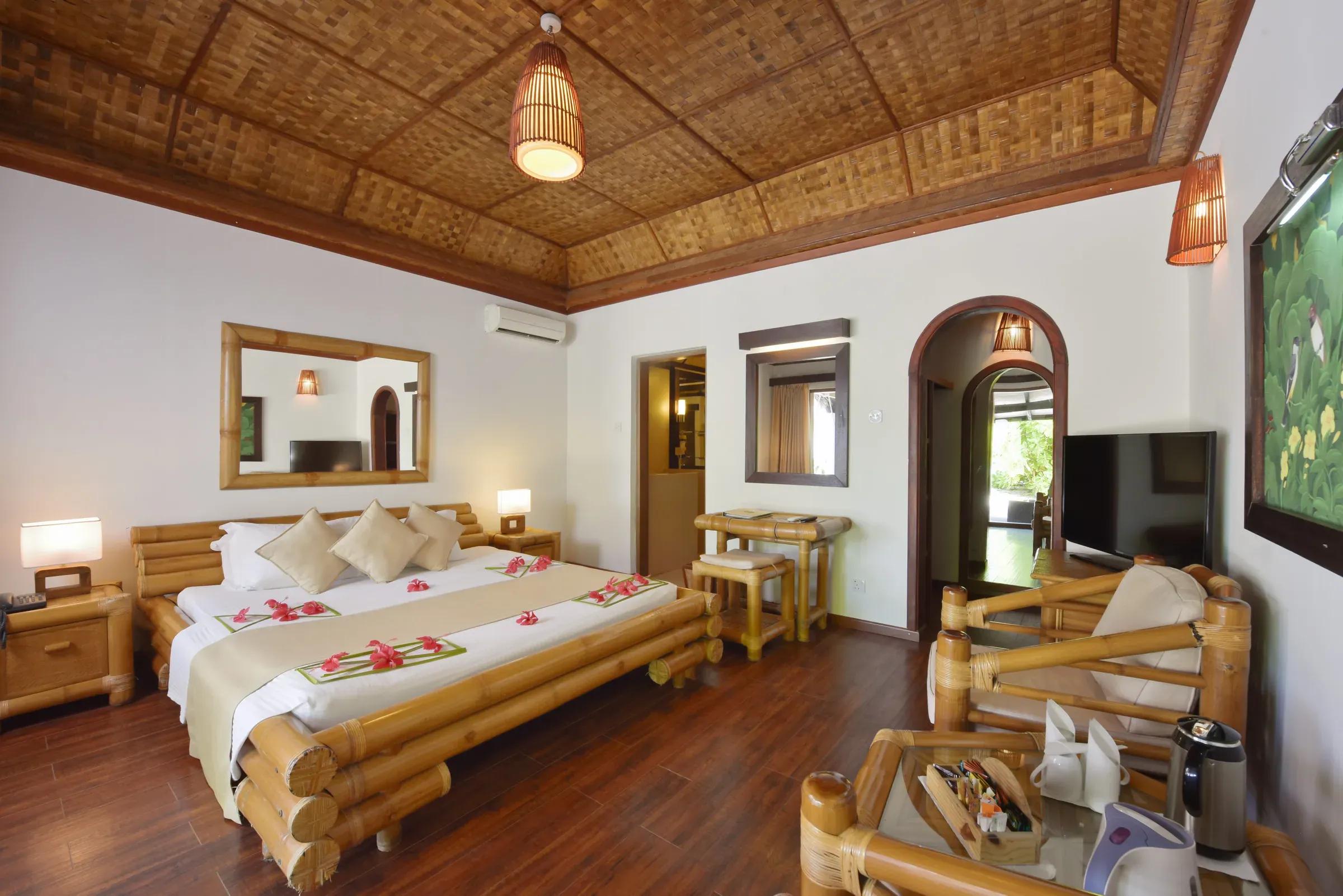 Interno della SUPERIOR BEACH BUNGALOW con letto matrimoniale e arredi in bambù al Angaga Island Resort & Spa.