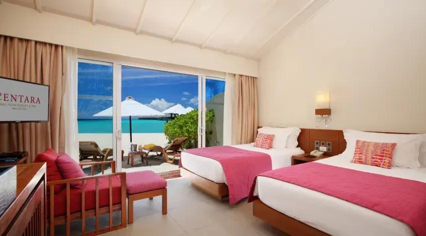 Interno della Lagoon View Beach Villa con due letti e vista sulla spiaggia al Centara Ras Fushi Resort & Spa Maldives.