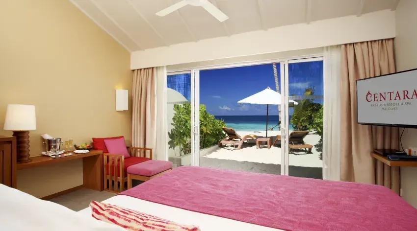 Interno della Lagoon View Beach Villa con letto e vista sulla spiaggia al Centara Ras Fushi Resort & Spa Maldives.