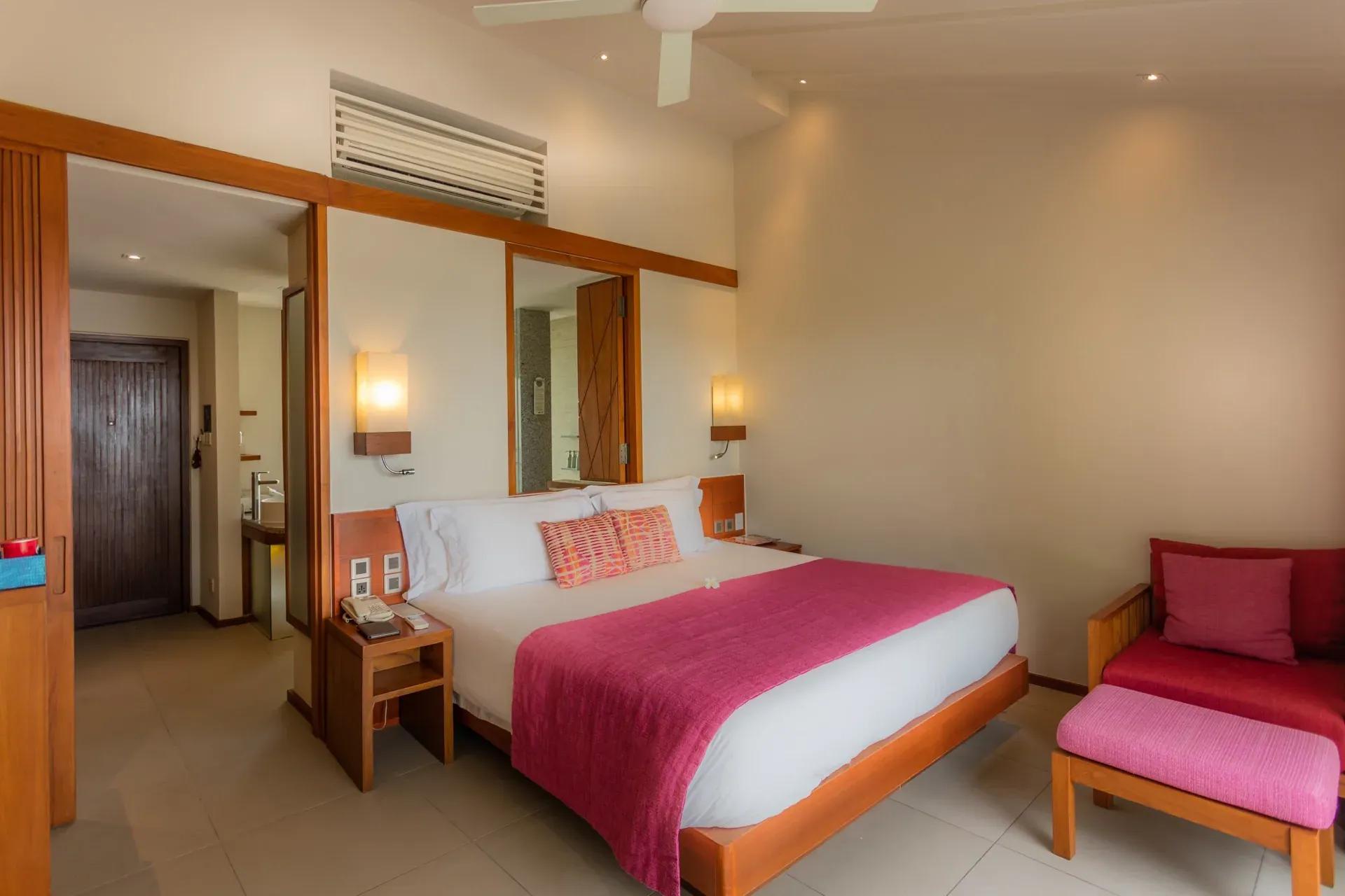 Interno della Lagoon View Beach Villa with Swirl Pool con letto matrimoniale e divano al Centara Ras Fushi Resort & Spa Maldives.