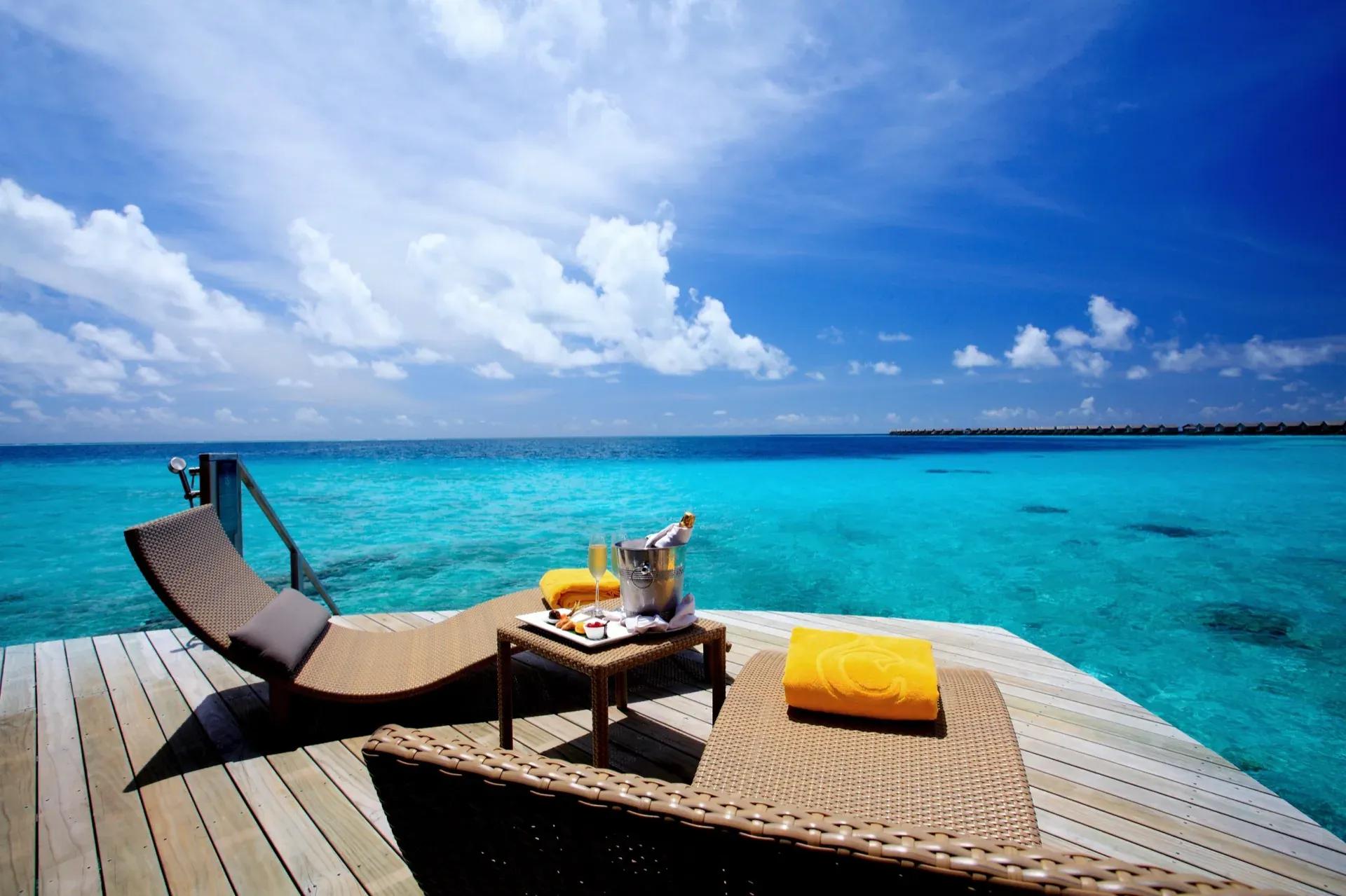Terrazza della Overwater Villa con lettini e vista sull'oceano al Centara Ras Fushi Resort & Spa Maldives