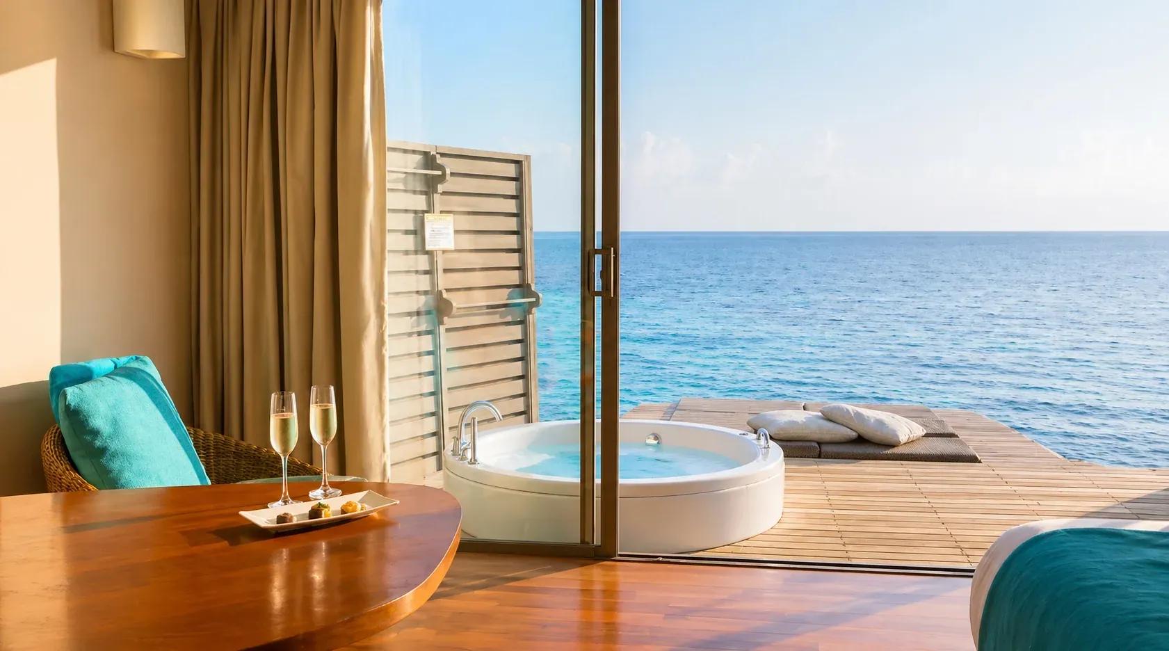 Interno della Overwater Villa with Swirl Pool con tavolino e vista sull'oceano al Centara Ras Fushi Resort & Spa Maldives.