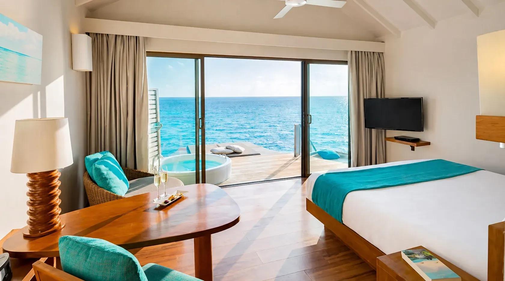 Vista interna della Sunset Overwater Villa with a Swirl Pool con vasca idromassaggio e vista sull'oceano al Centara Ras Fushi Resort & Spa Maldives.