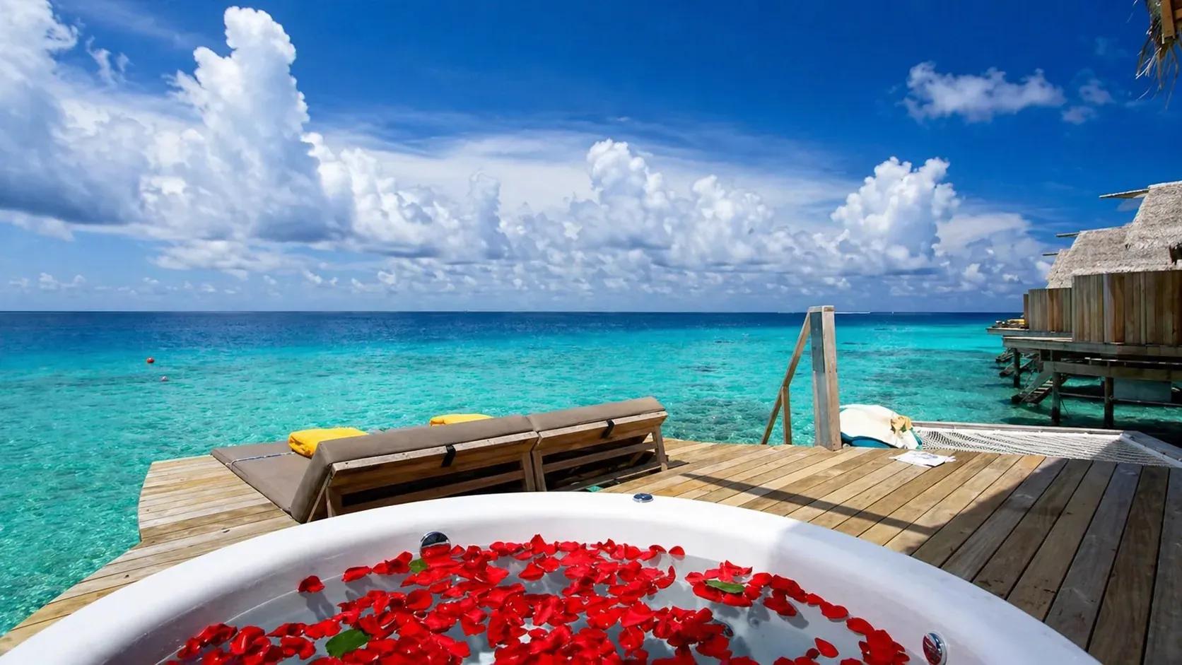 Vista sulla terrazza della Sunset Overwater Villa with a Swirl Pool con piscina idromassaggio e lettini al Centara Ras Fushi Resort & Spa Maldives.