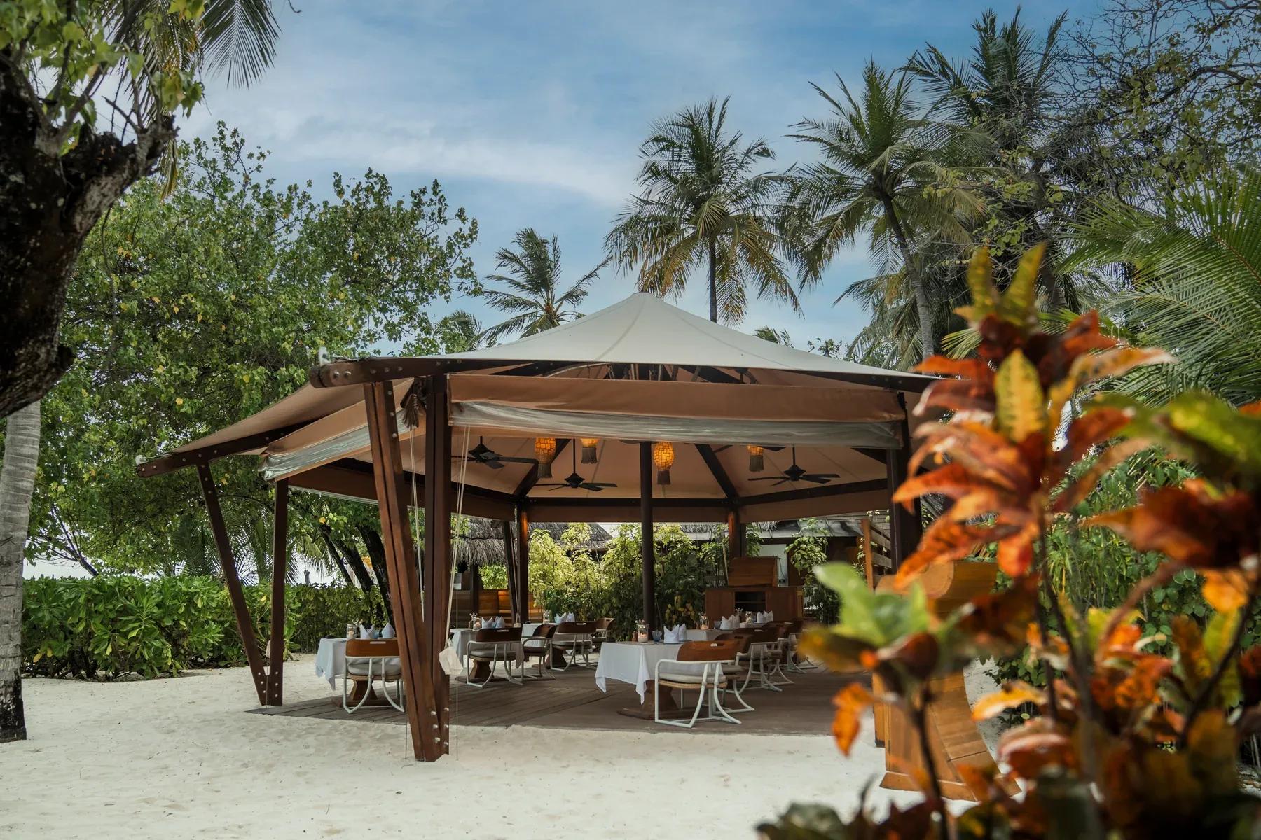 Ristorante Alizee con tavoli sulla sabbia e palme al Constance Moofushi.