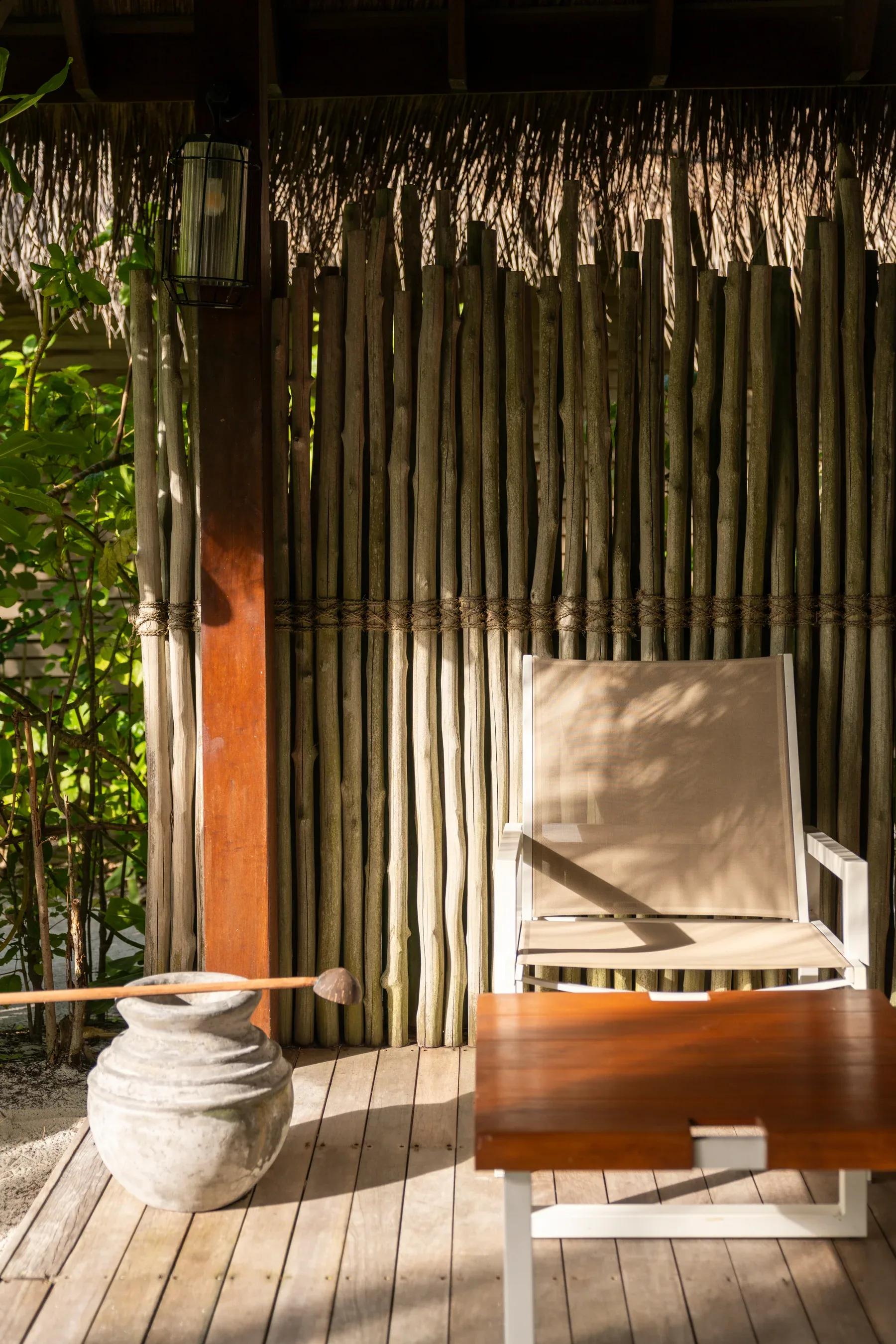 Area esterna della Beach Villas con sedia e tavolo in legno al Constance Moofushi.