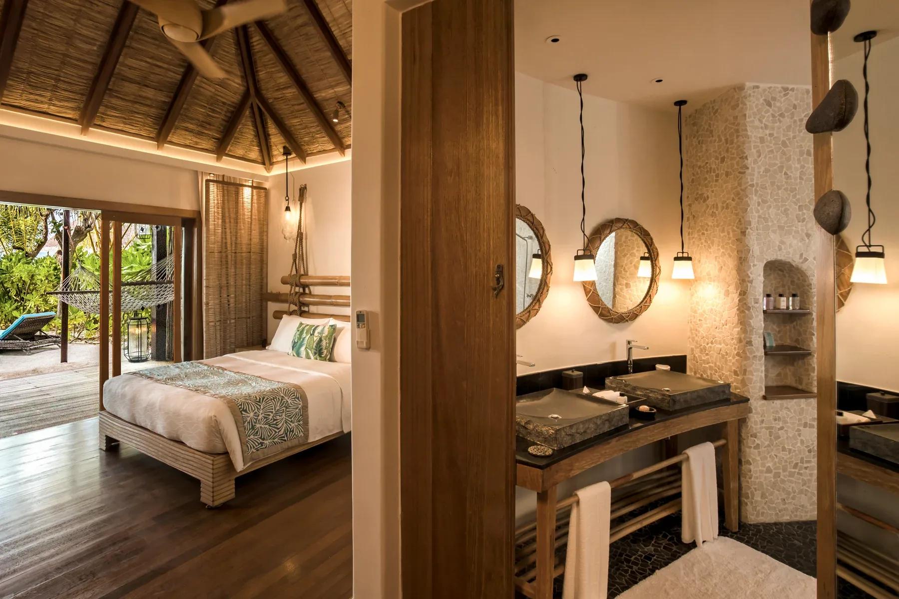 Interno delle Beach Villas con letto matrimoniale e terrazza vista giardino al Constance Moofushi.