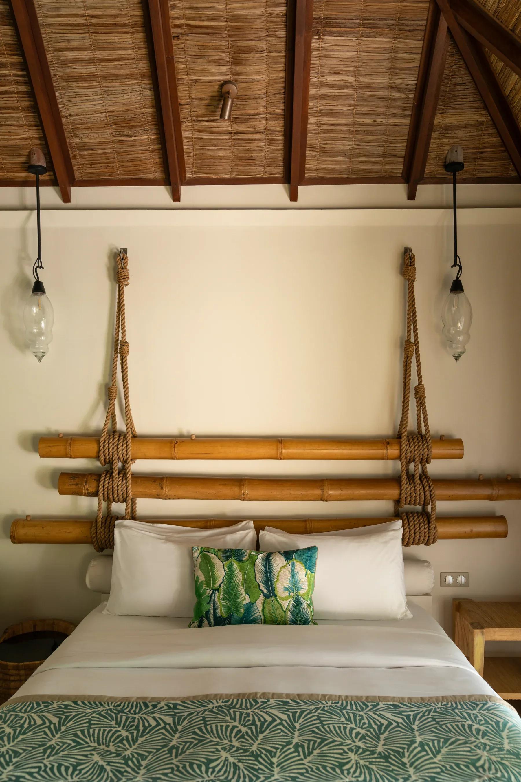 Letto con testiera in bambù e cuscini decorativi nella Beach Villas del Constance Moofushi.