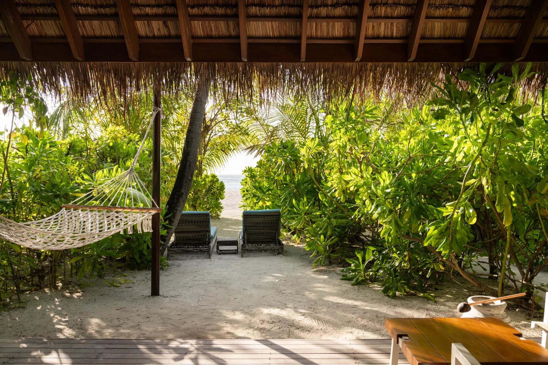 Amaca e lettini sulla veranda della Beach Villas con vista su giardino tropicale al Constance Moofushi.
