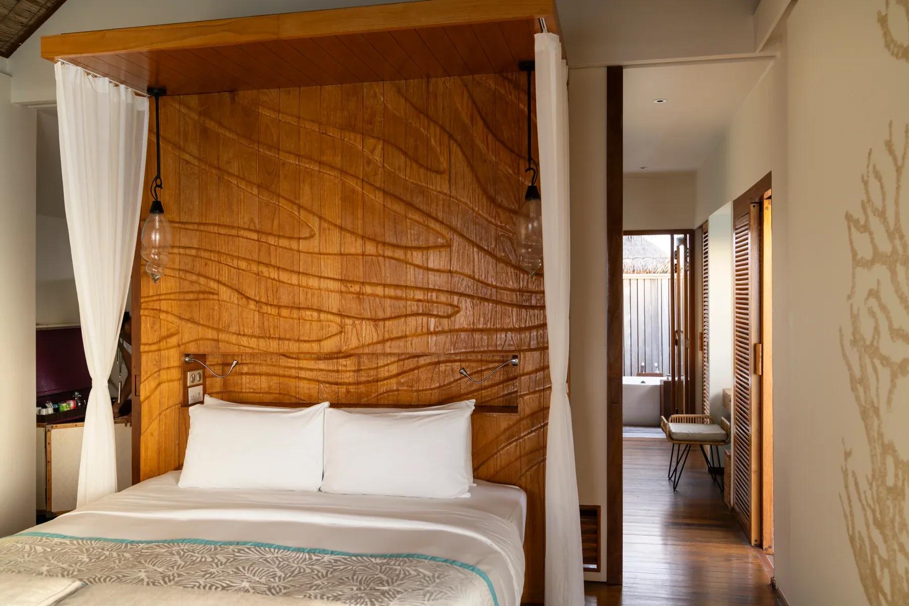 Interno della Senior Water Villas con letto matrimoniale e vista sul bagno al Constance Moofushi.