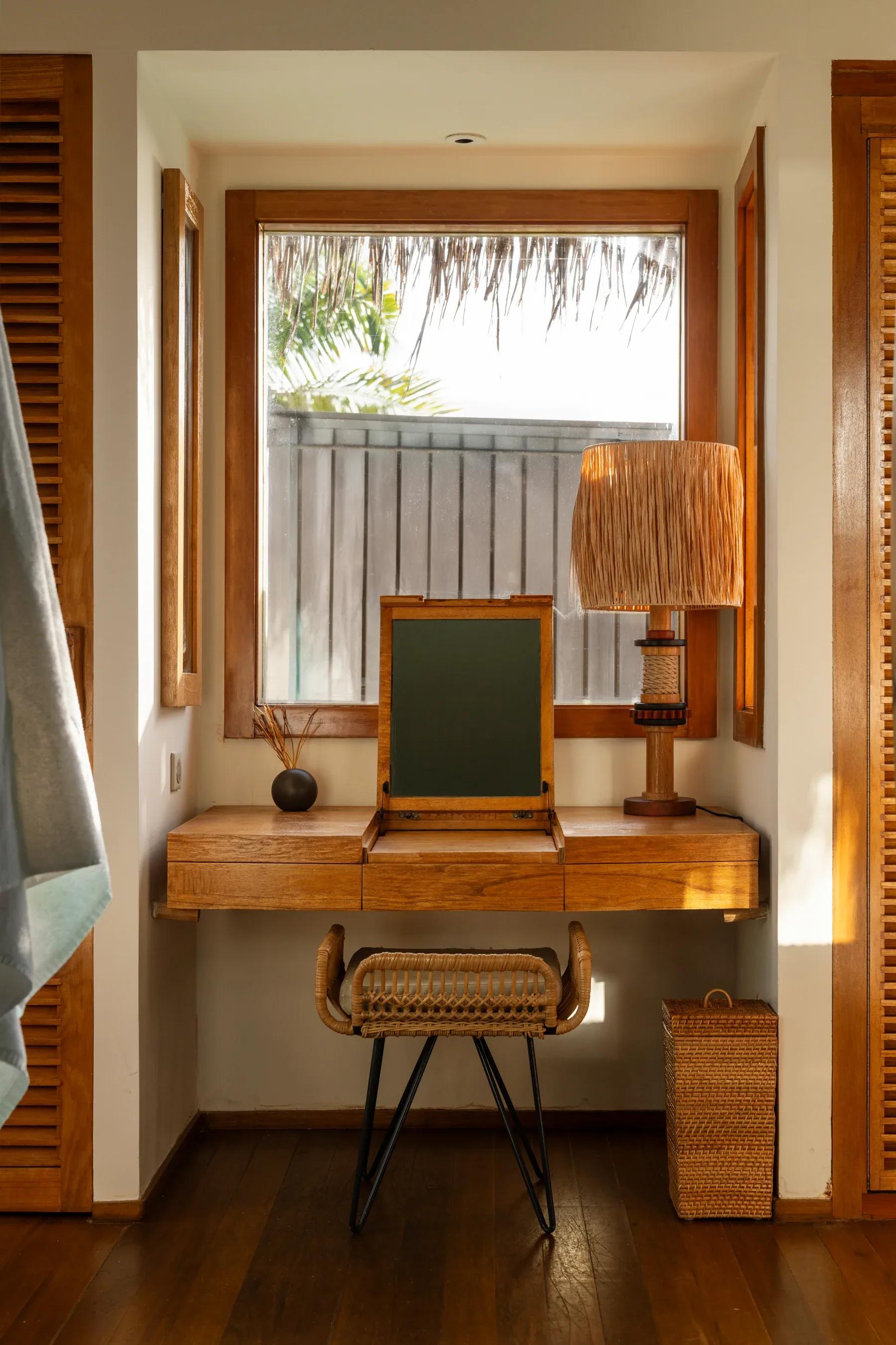 Angolo lettura in legno con finestra e lampada nella Senior Water Villas del Constance Moofushi.