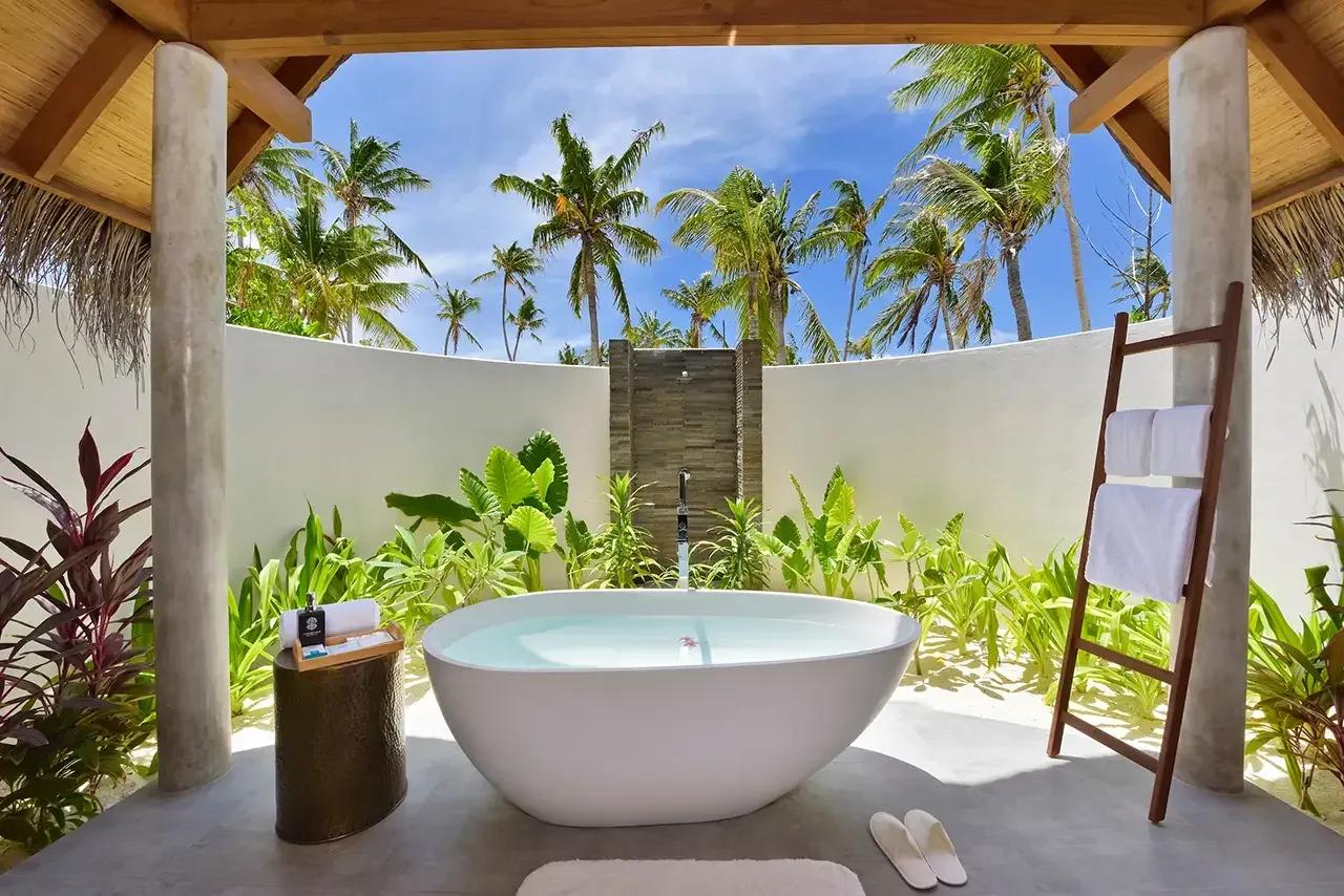 Vasca da bagno all'aperto e palme tropicali nella Pool Beach Villa Sunset al Fushifaru Maldives.