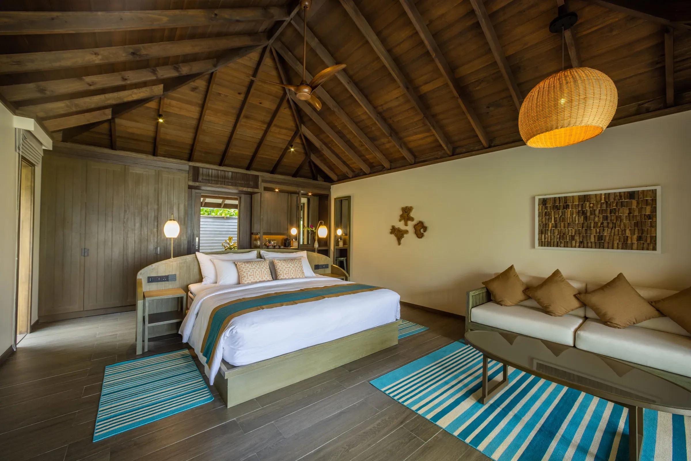 Camera della Dheru Beach Pool Villa con letto matrimoniale e divano al Jawakara Islands Maldives