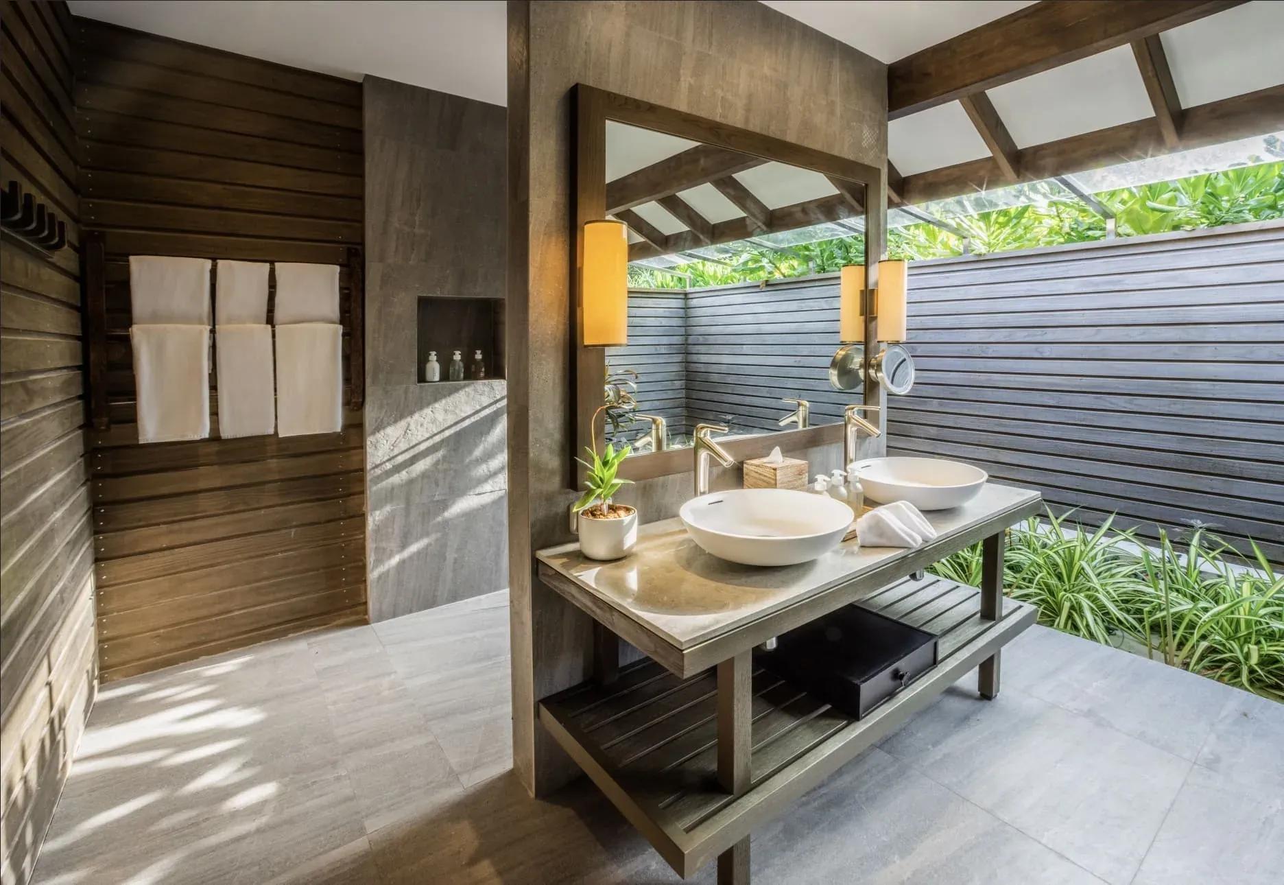 Bagno della Dheru Beach Villa con doppio lavabo e illuminazione calda al Jawakara Islands Maldives.