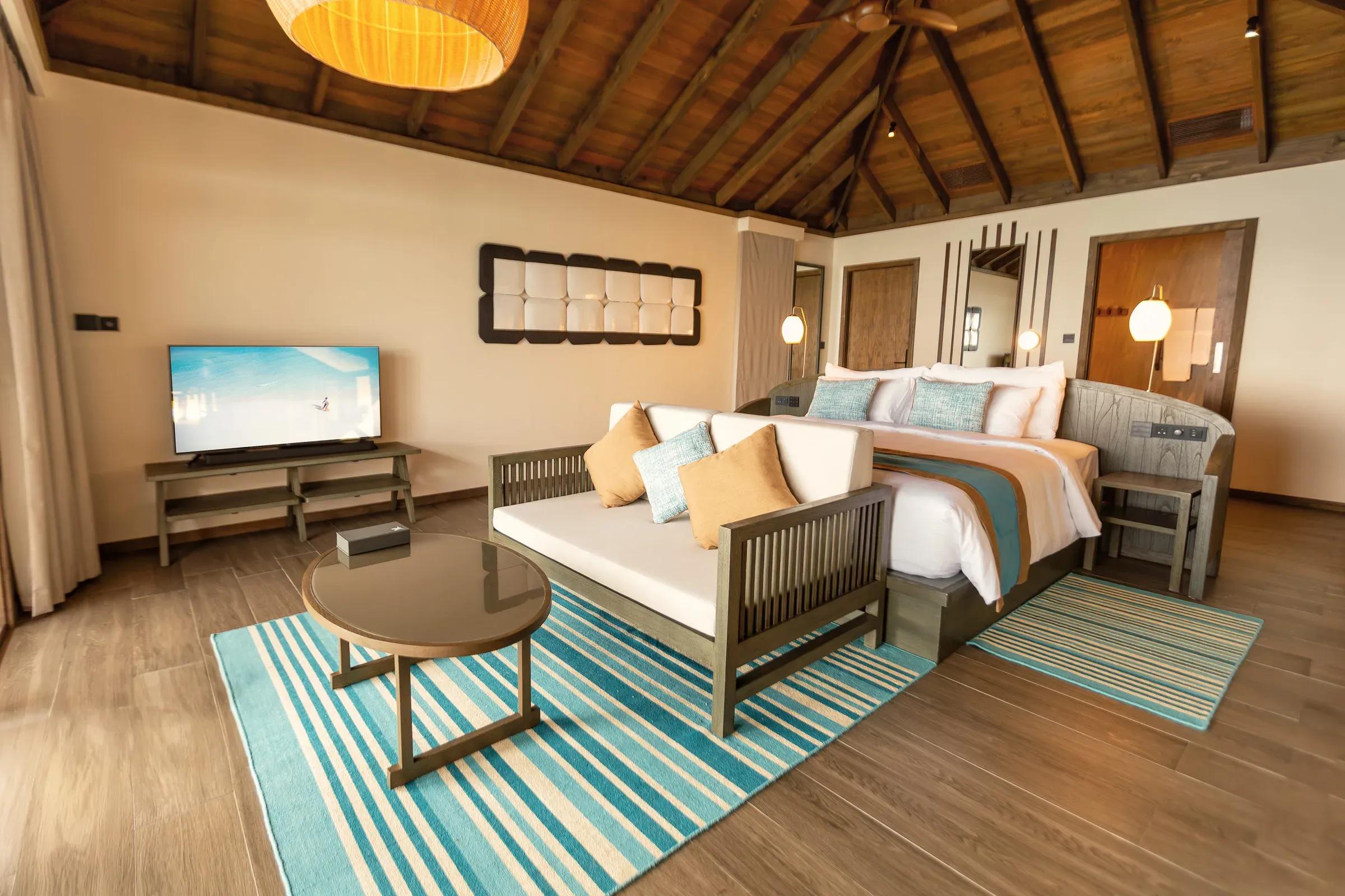 Camera da letto con letto king size e divano della Dheru Water Pool Villa al Jawakara Islands Maldives