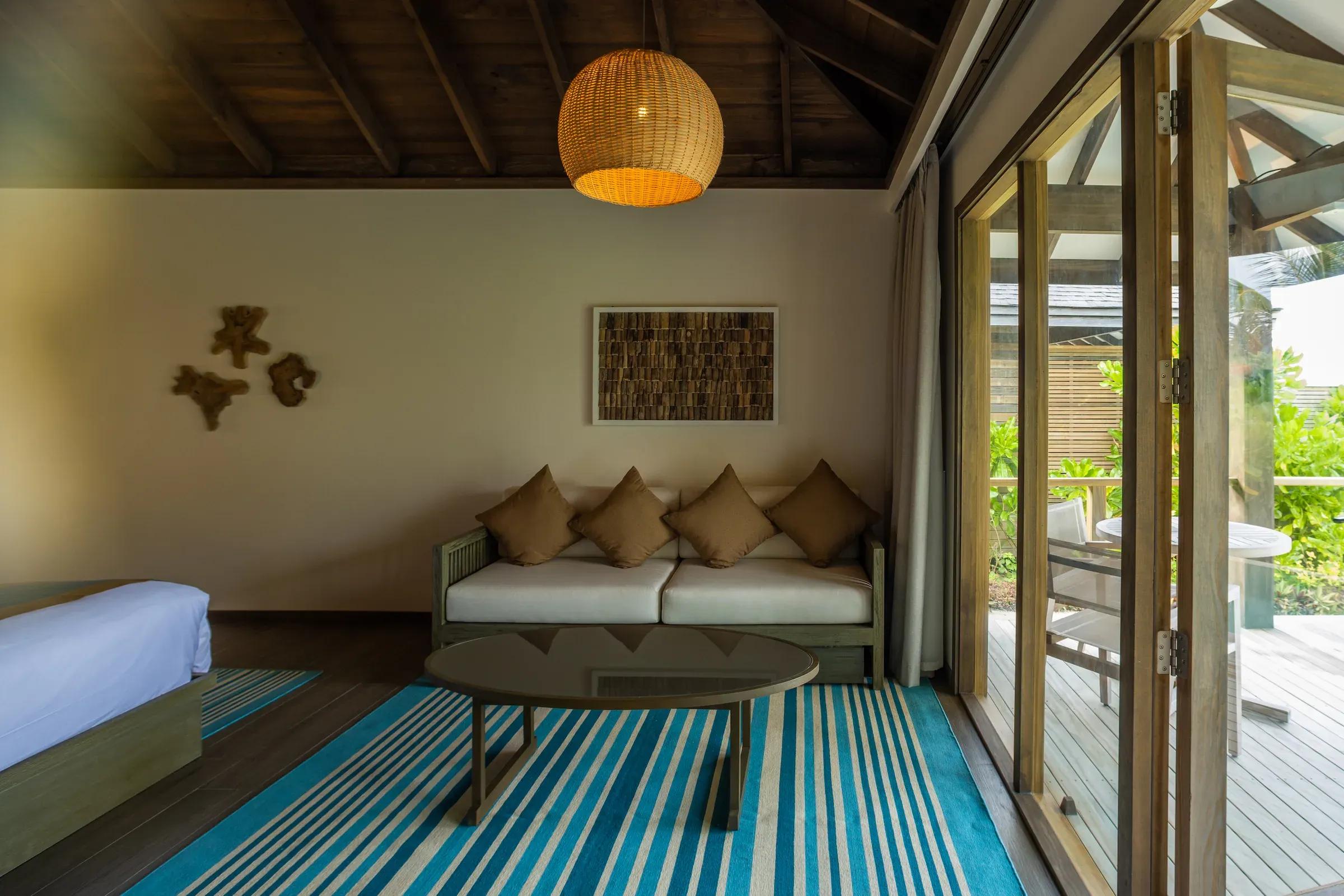 Zona soggiorno con divano e tappeto a righe nella Mabin Beach Villa del Jawakara Islands Maldives