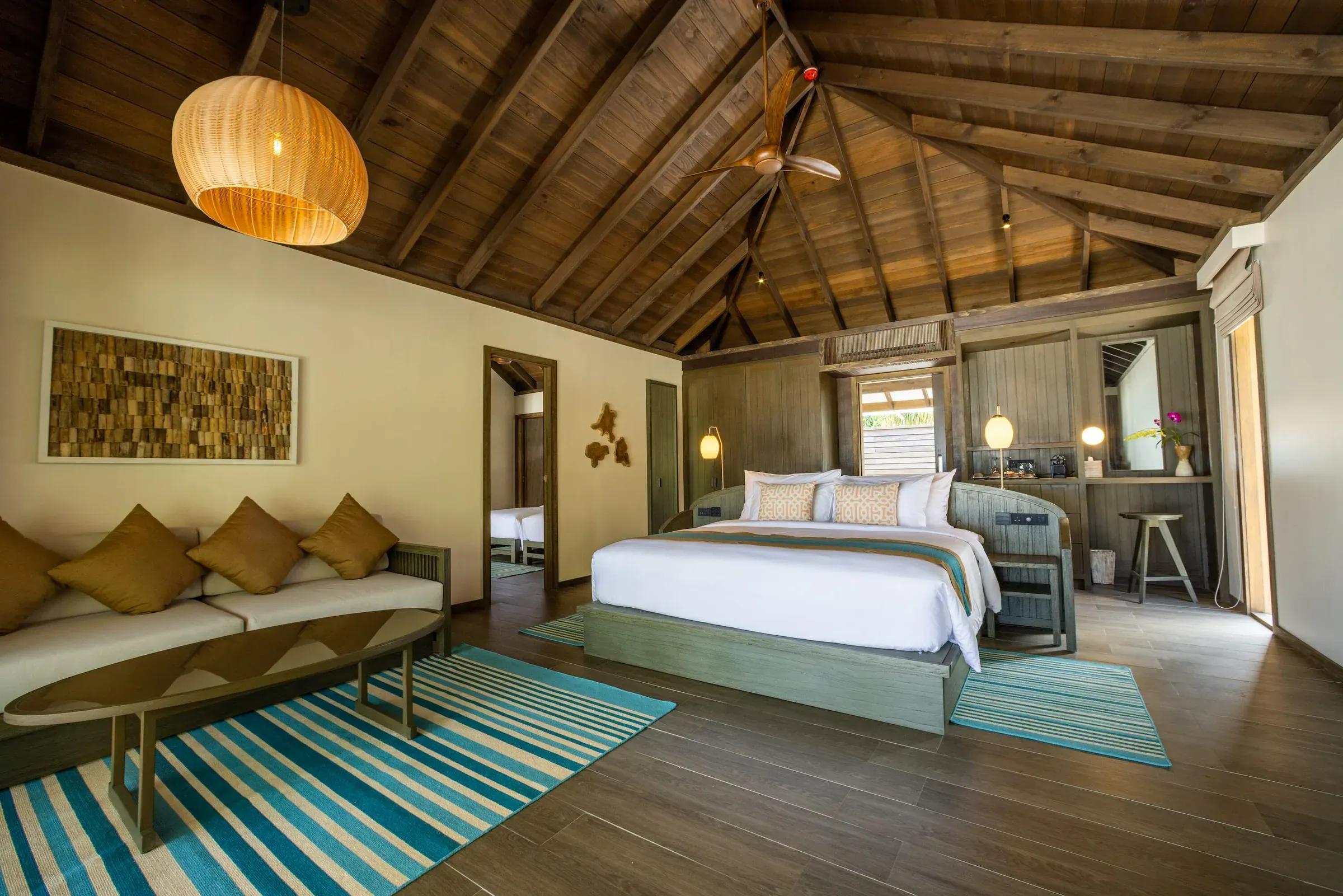Camera della Mabin Three Bedroom Villa con letto matrimoniale, divano e lampada a soffitto al Jawakara Islands Maldives.