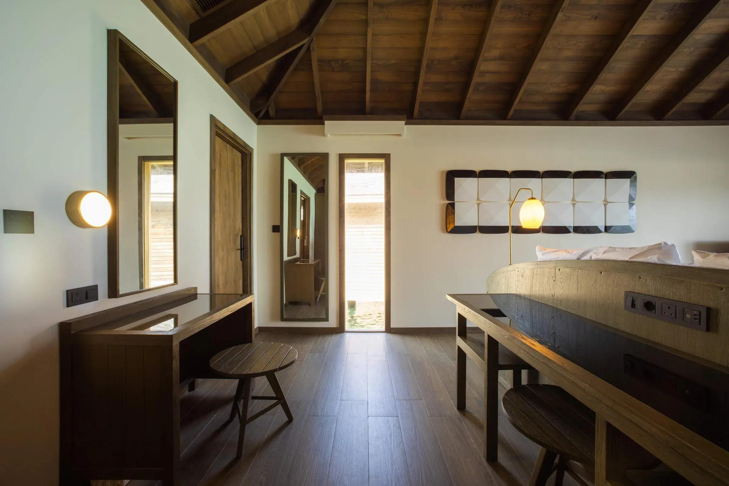 Camera da letto con soffitto in legno e scrivania nella Mabin Water Pool Villa al Jawakara Islands Maldives
