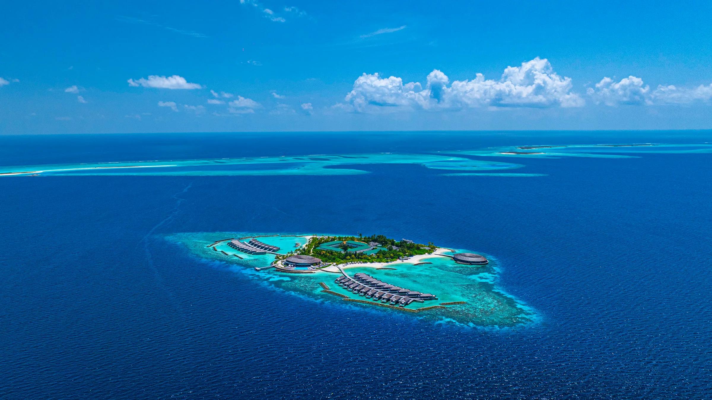Vista aerea del Kagi Maldives Spa Island con bungalows sull'acqua e spiagge bianche.