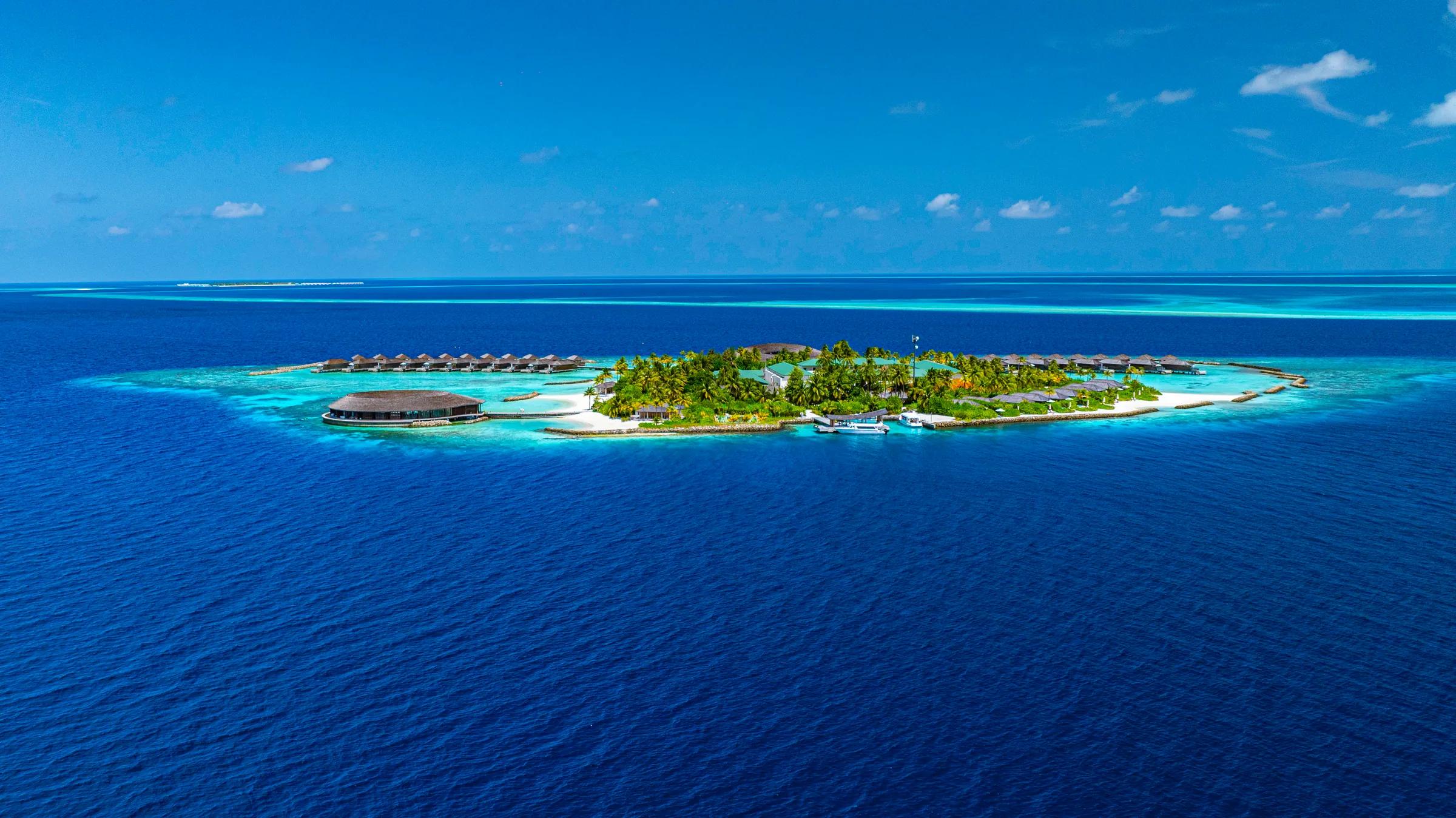 Vista aerea dell'isola privata con laguna turchese e ville sull'acqua al Kagi Maldives Spa Island