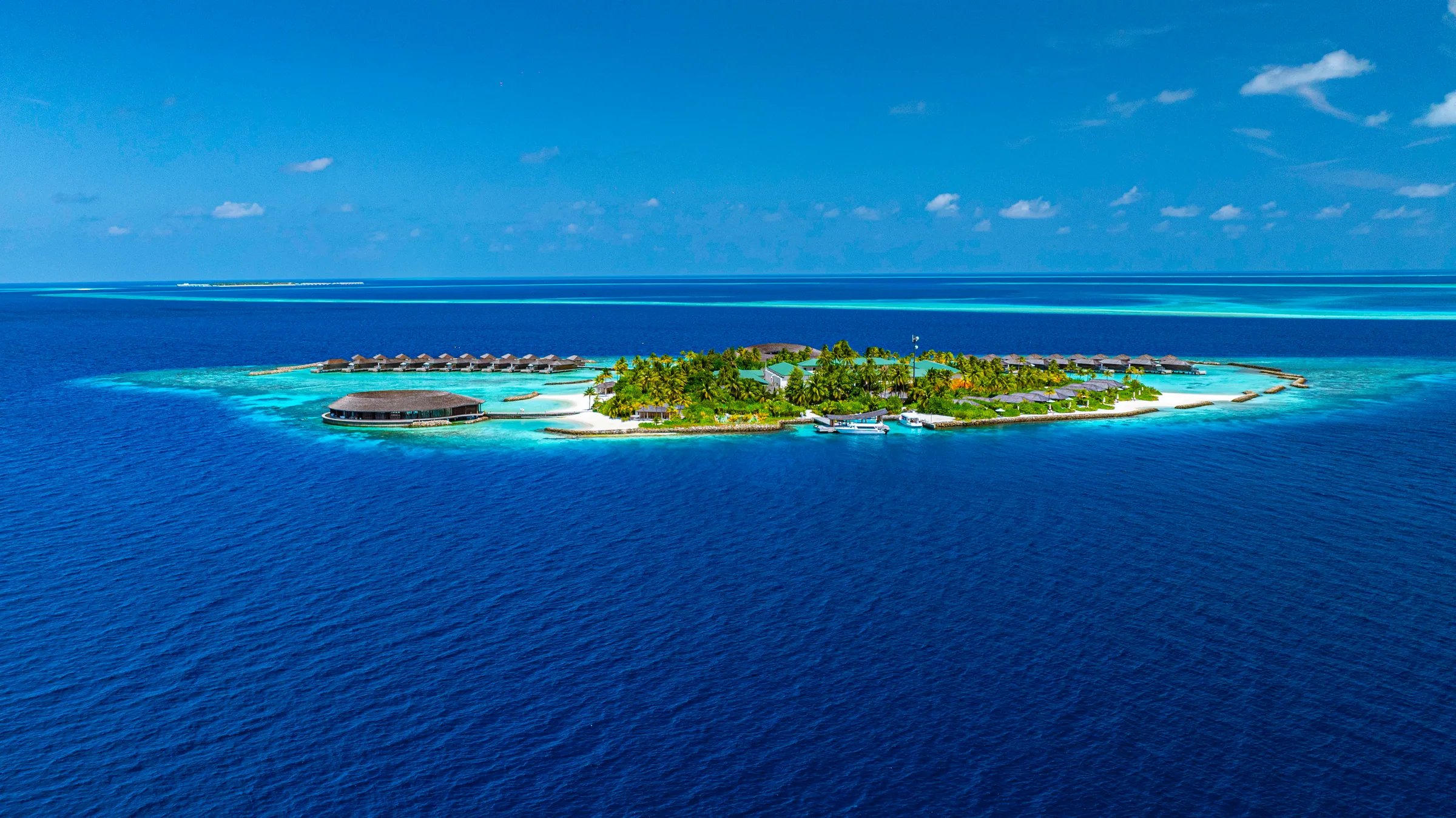 Vista aerea dell'isola privata con laguna turchese e ville sull'acqua al Kagi Maldives Spa Island