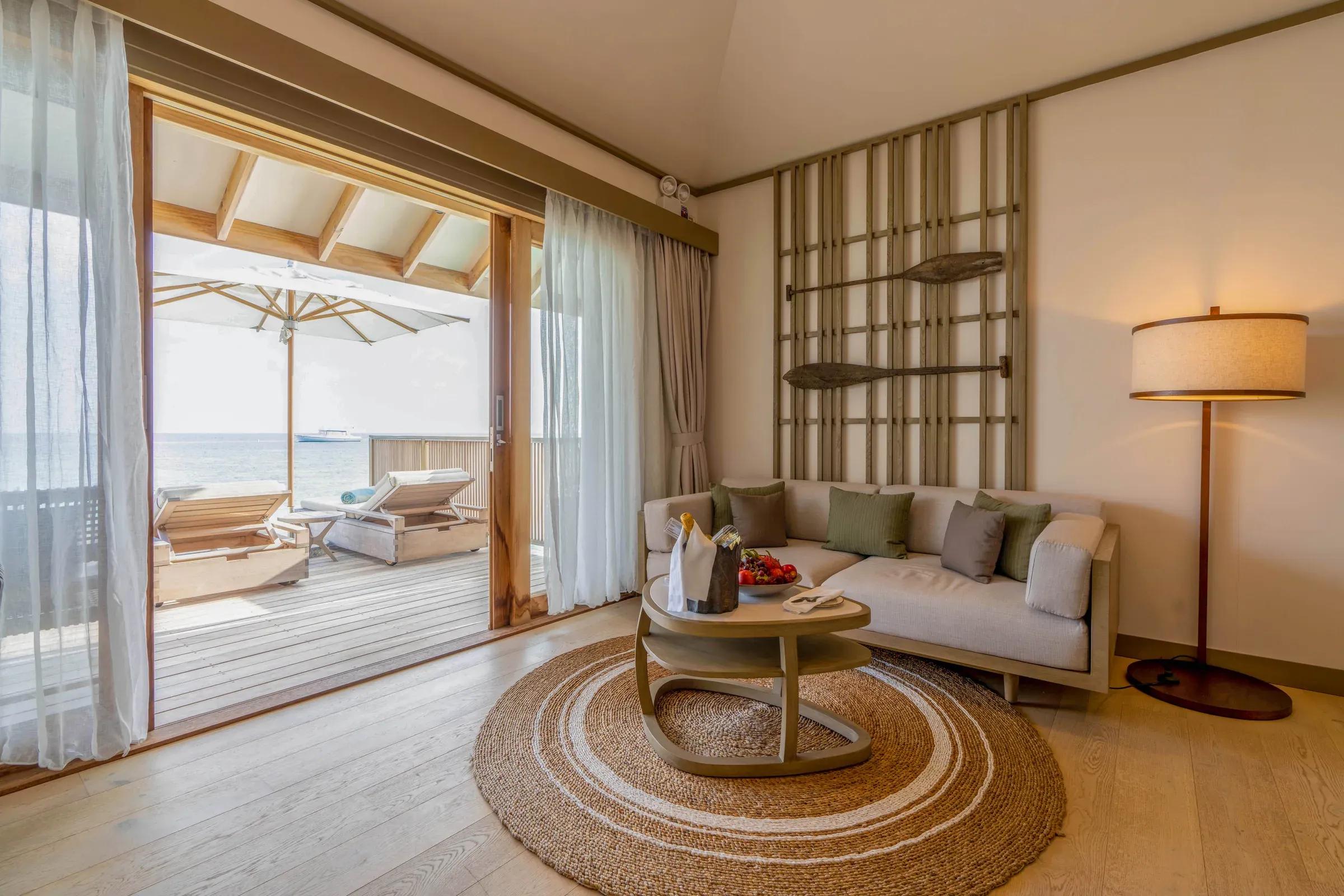 Soggiorno con divano e terrazza con vista mare della Ocean Pool Villa al Kagi Maldives Spa Island.