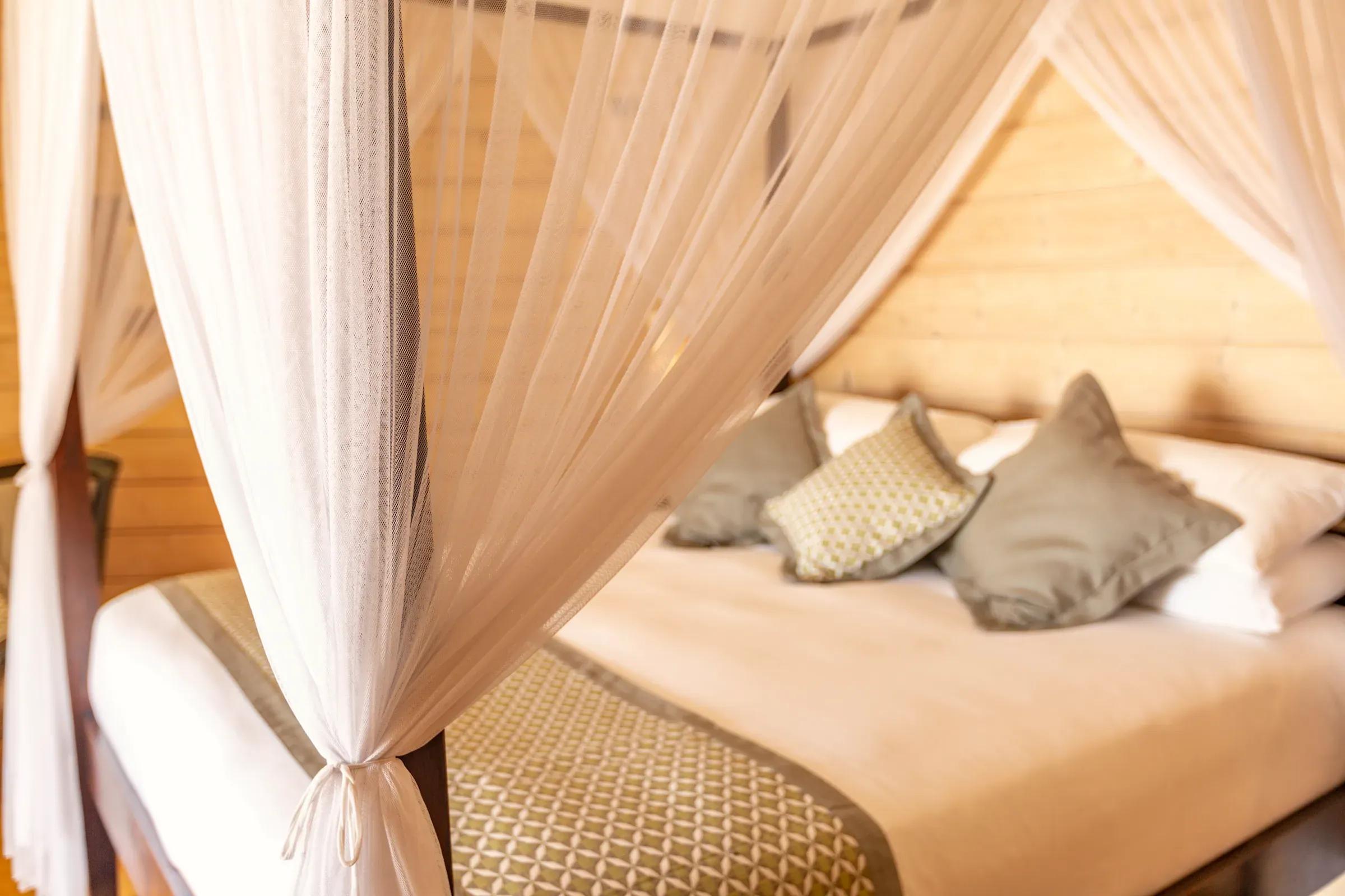 Letto a baldacchino con tende e cuscini decorativi nella Premium Jacuzzi Beach Villa del Komandoo Island Resort & Spa.