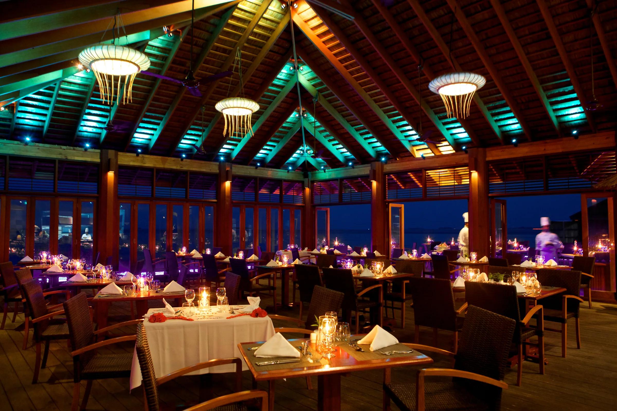 Buffet Restaurant con tavoli apparecchiati e luci soffuse al Kuredu Island Resort & Spa.