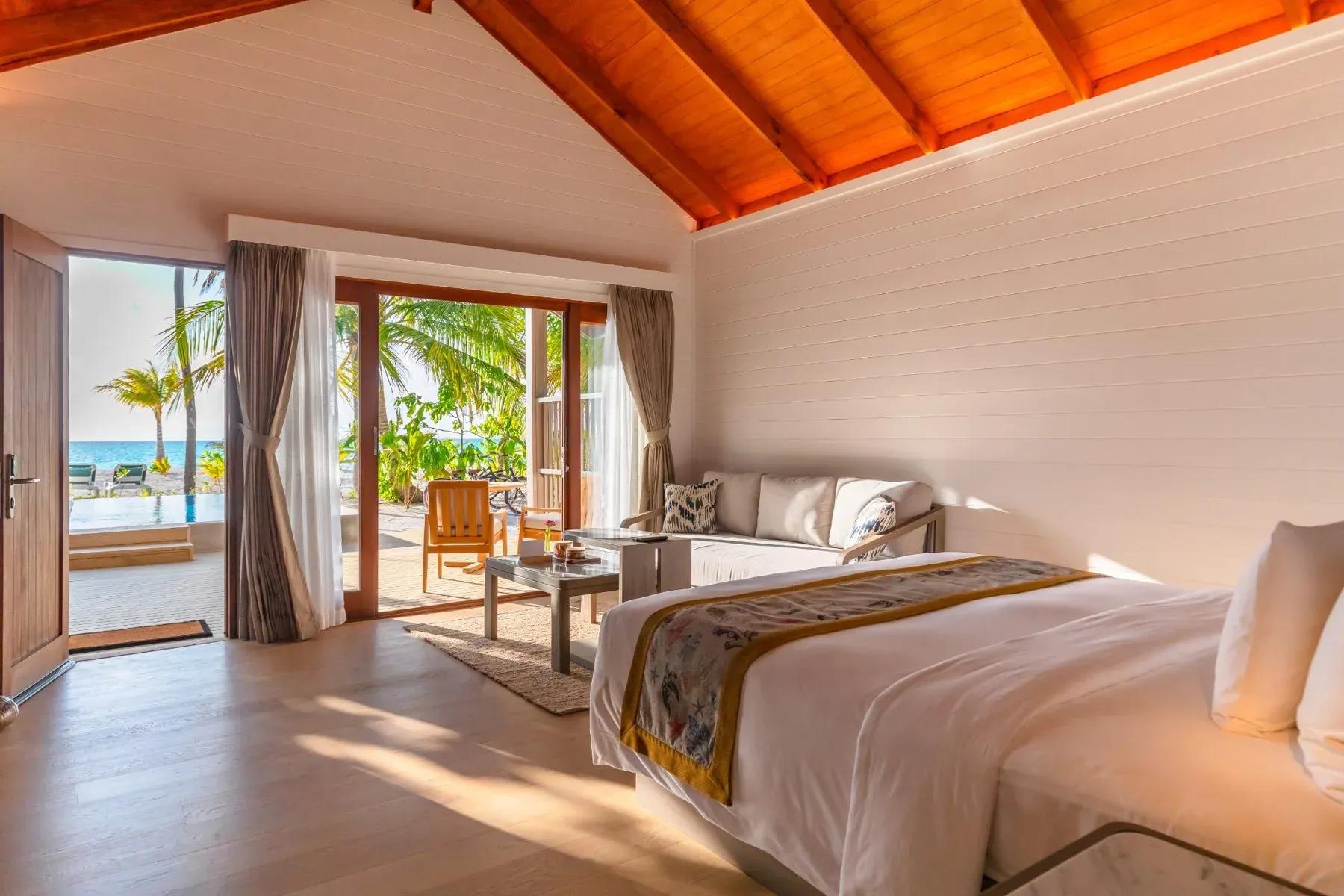 Beach Pool Villa con letto, divano e vista piscina e mare del Meeru Island Resort & Spa.