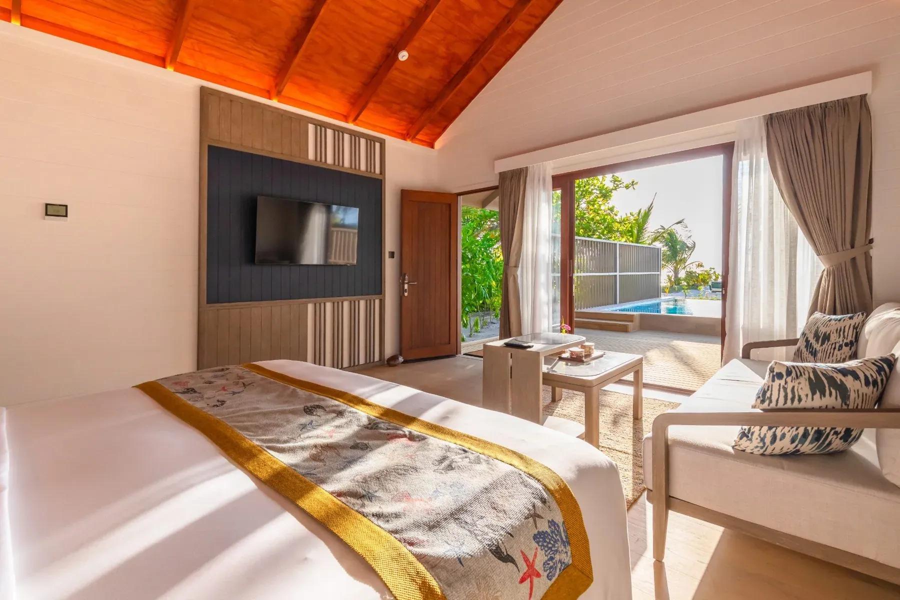 Interno della Beach Pool Villa con letto matrimoniale e area soggiorno al Meeru Island Resort & Spa.