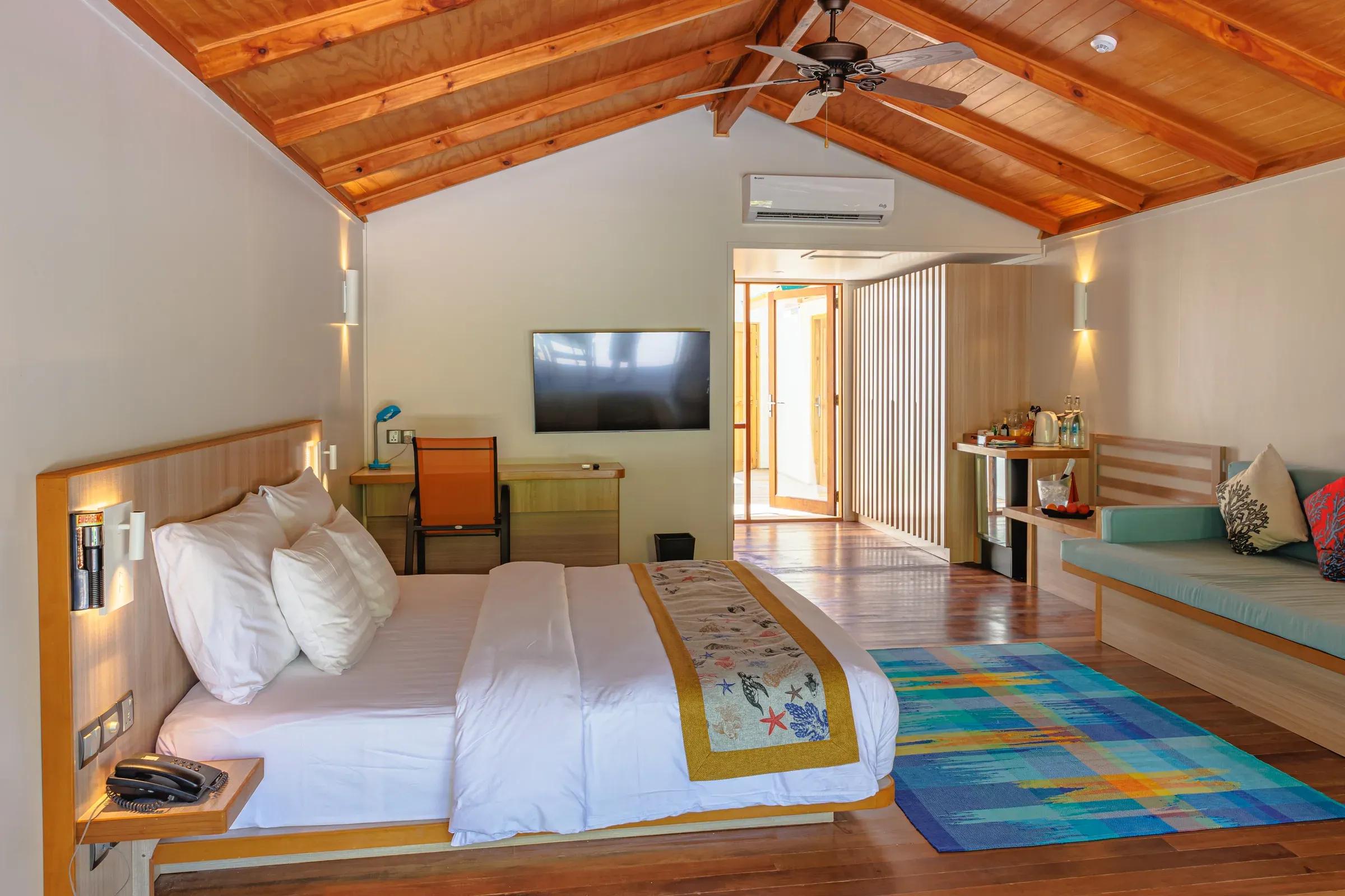 Interno della Family Villa con letto matrimoniale e divano al Meeru Island Resort & Spa.