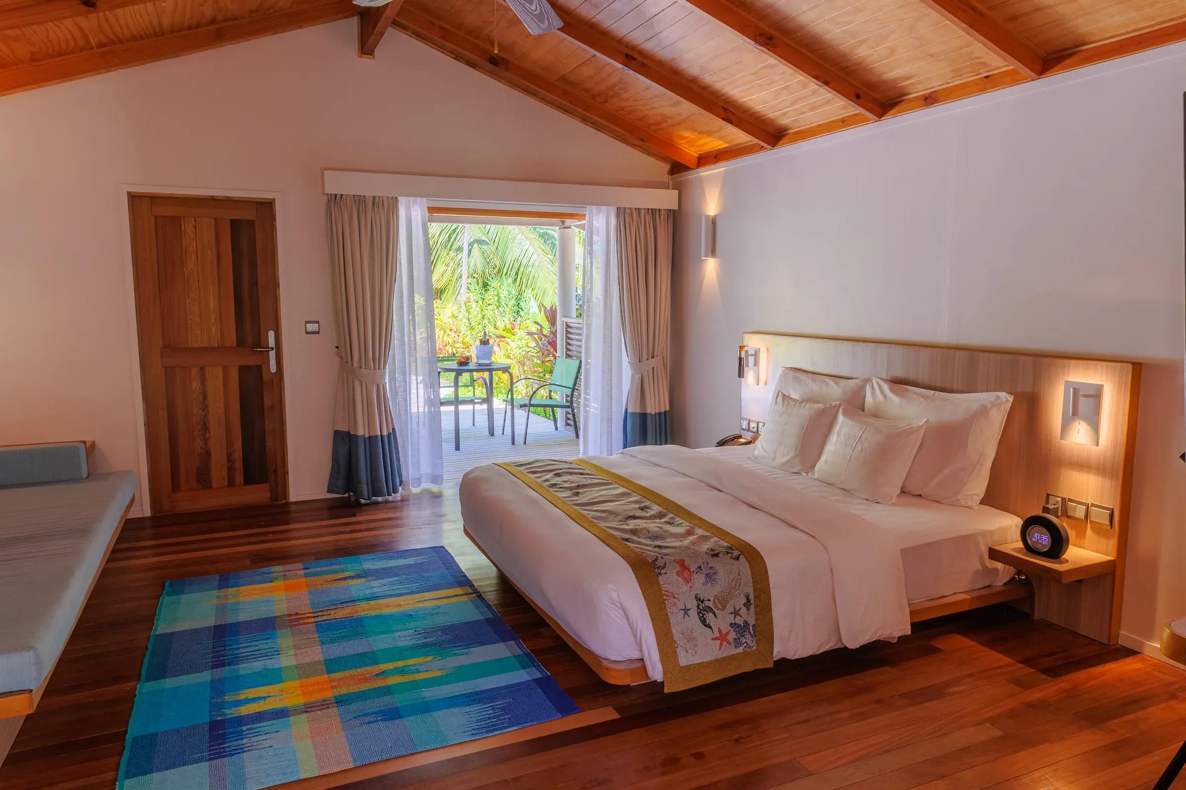 Camera da letto della Family Villa con letto matrimoniale e vista su terrazza e palme del Meeru Island Resort & Spa
