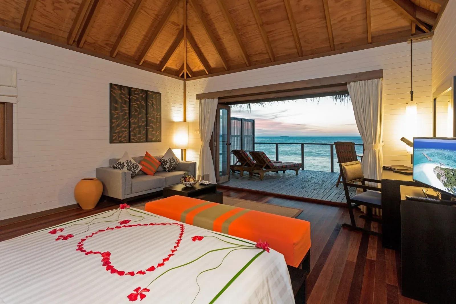Camera con letto, divano e terrazza con vista mare della Jacuzzi Water Villa al Meeru Island Resort & Spa