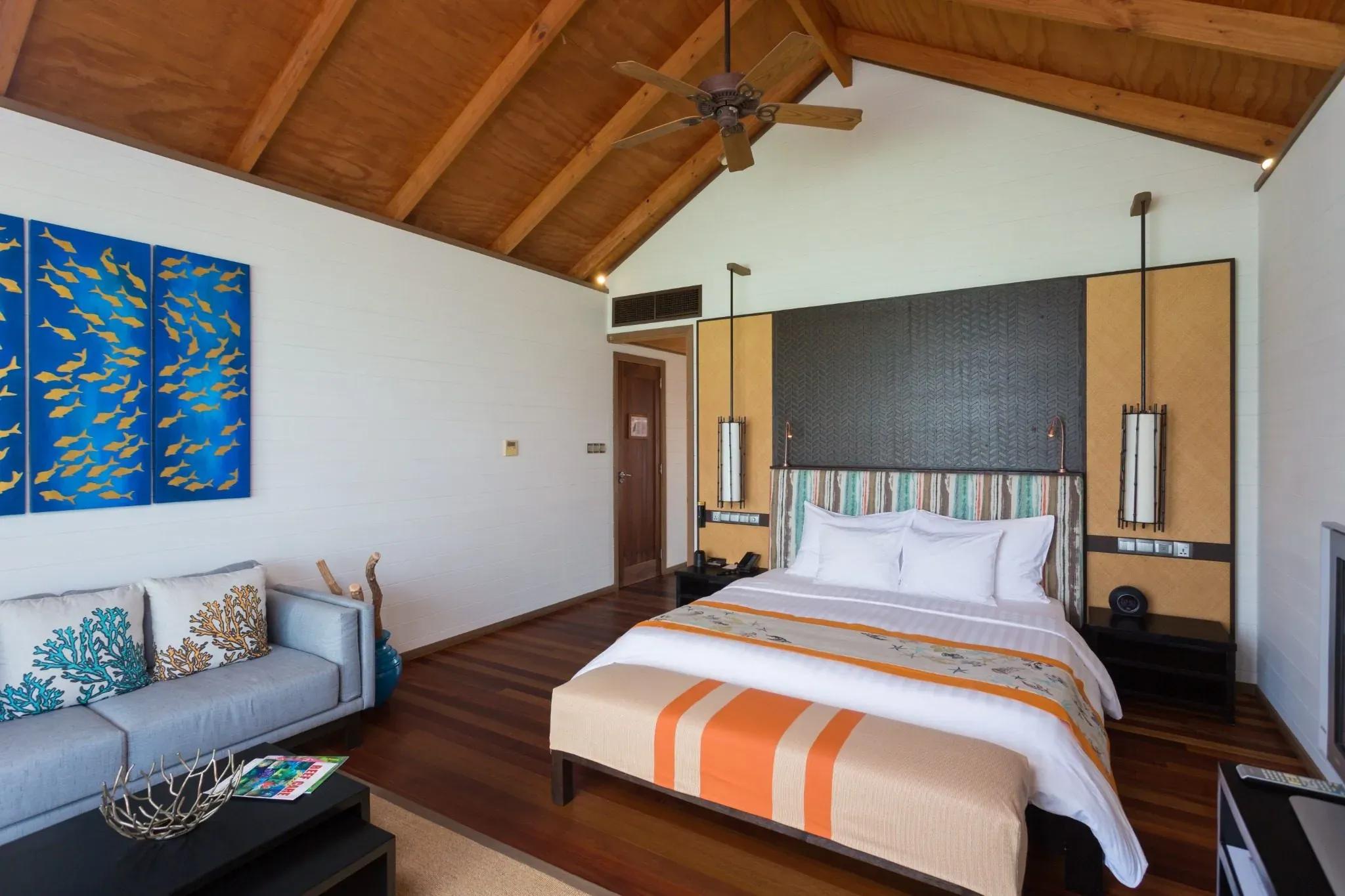 Interno della Jacuzzi Water Villa con letto matrimoniale e divano al Meeru Island Resort & Spa.