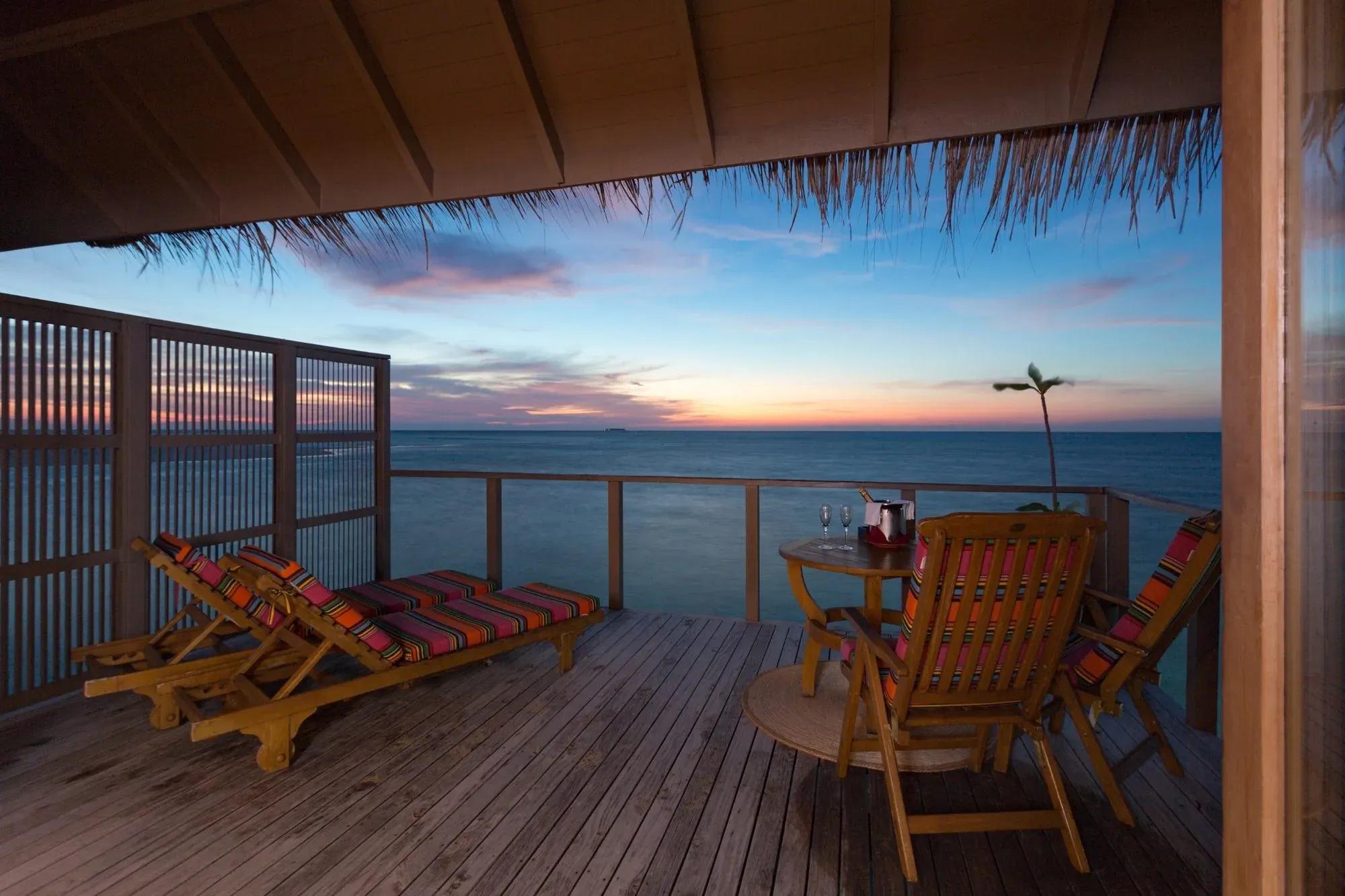 Terrazza della Ocean Villa con lettini e tavolo vista oceano al tramonto, Meeru Island Resort & Spa.