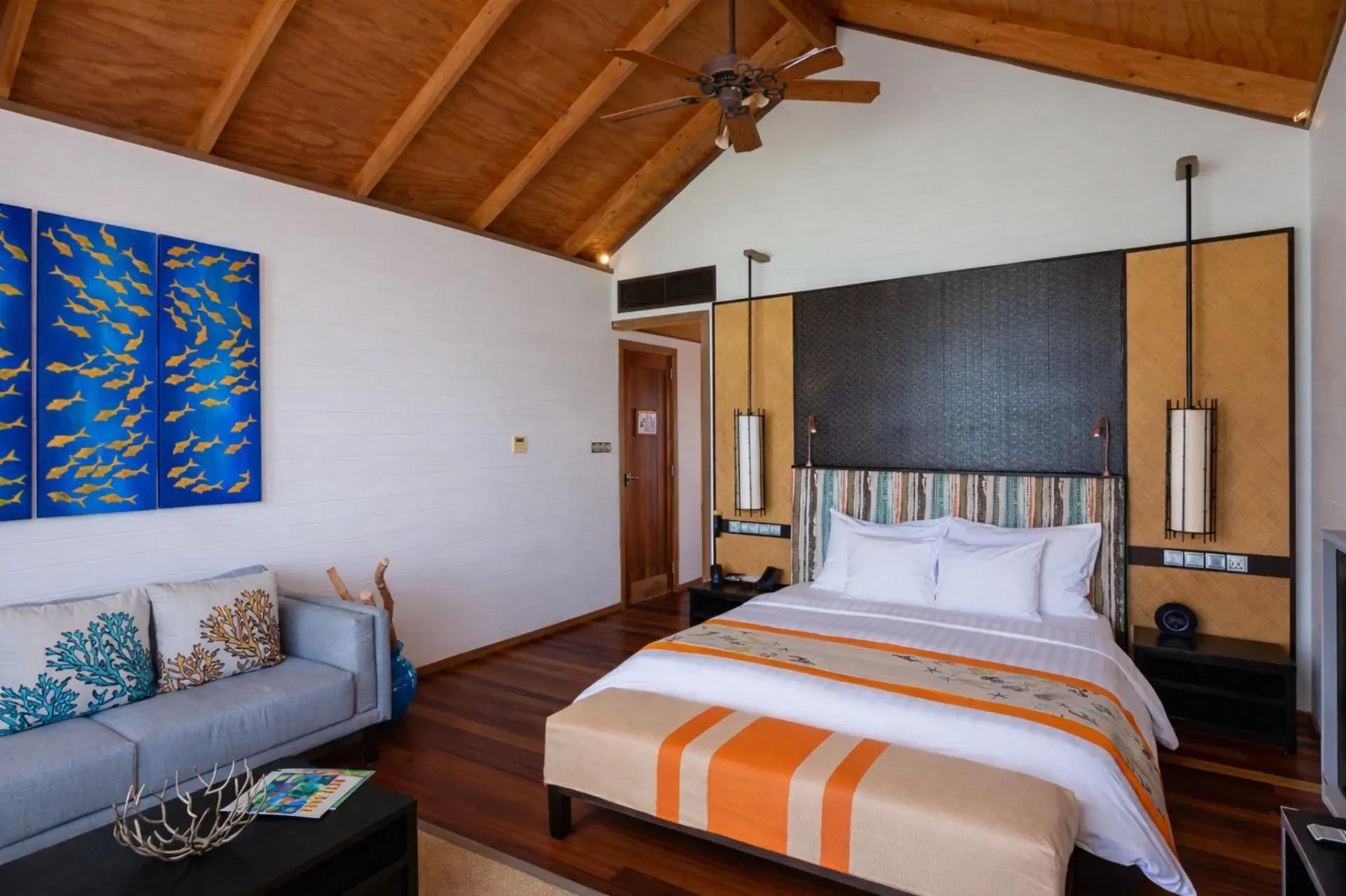 Letto matrimoniale e divano in soggiorno della Ocean Villa al Meeru Island Resort & Spa.