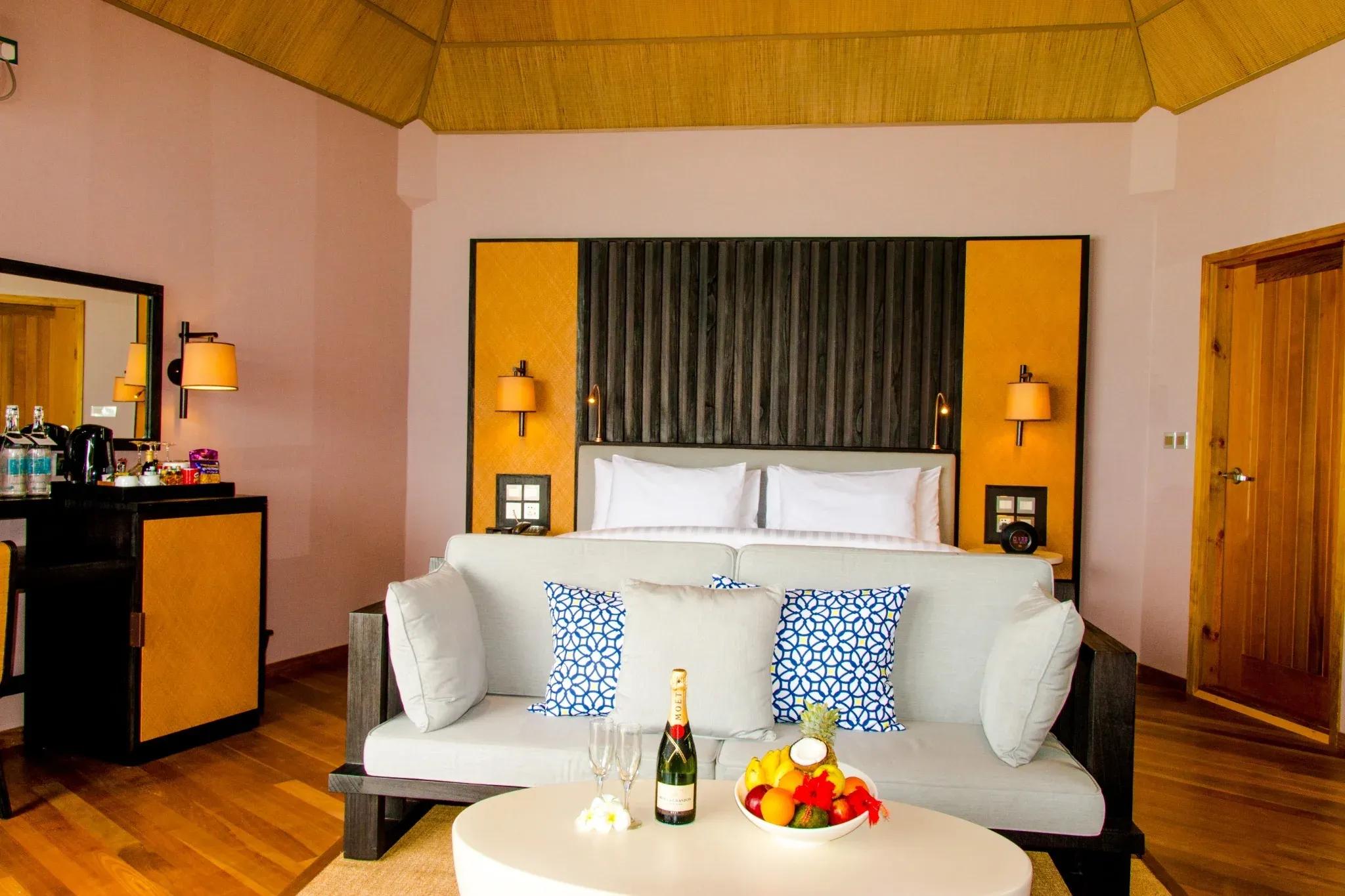 Interno della Water Front Villa con letto matrimoniale, divano e tavolino al Meeru Island Resort & Spa.