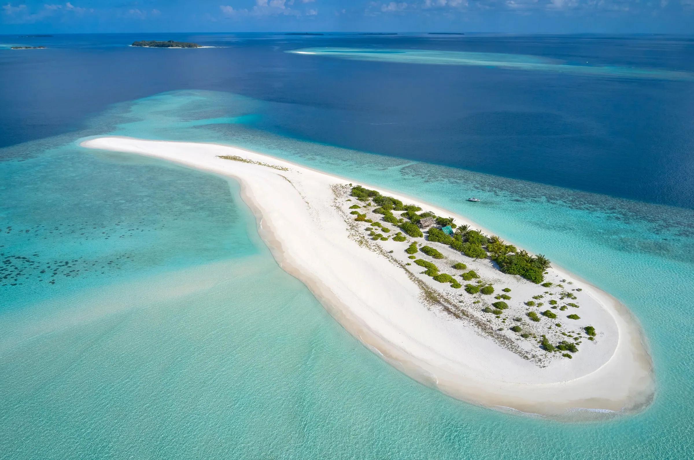 Vista aerea di un'incontaminata lingua di sabbia bianca che si estende nelle acque turchesi dell'Oceano Indiano, un'escursione esclusiva del Royal Island Resort & Spa alle Maldive.