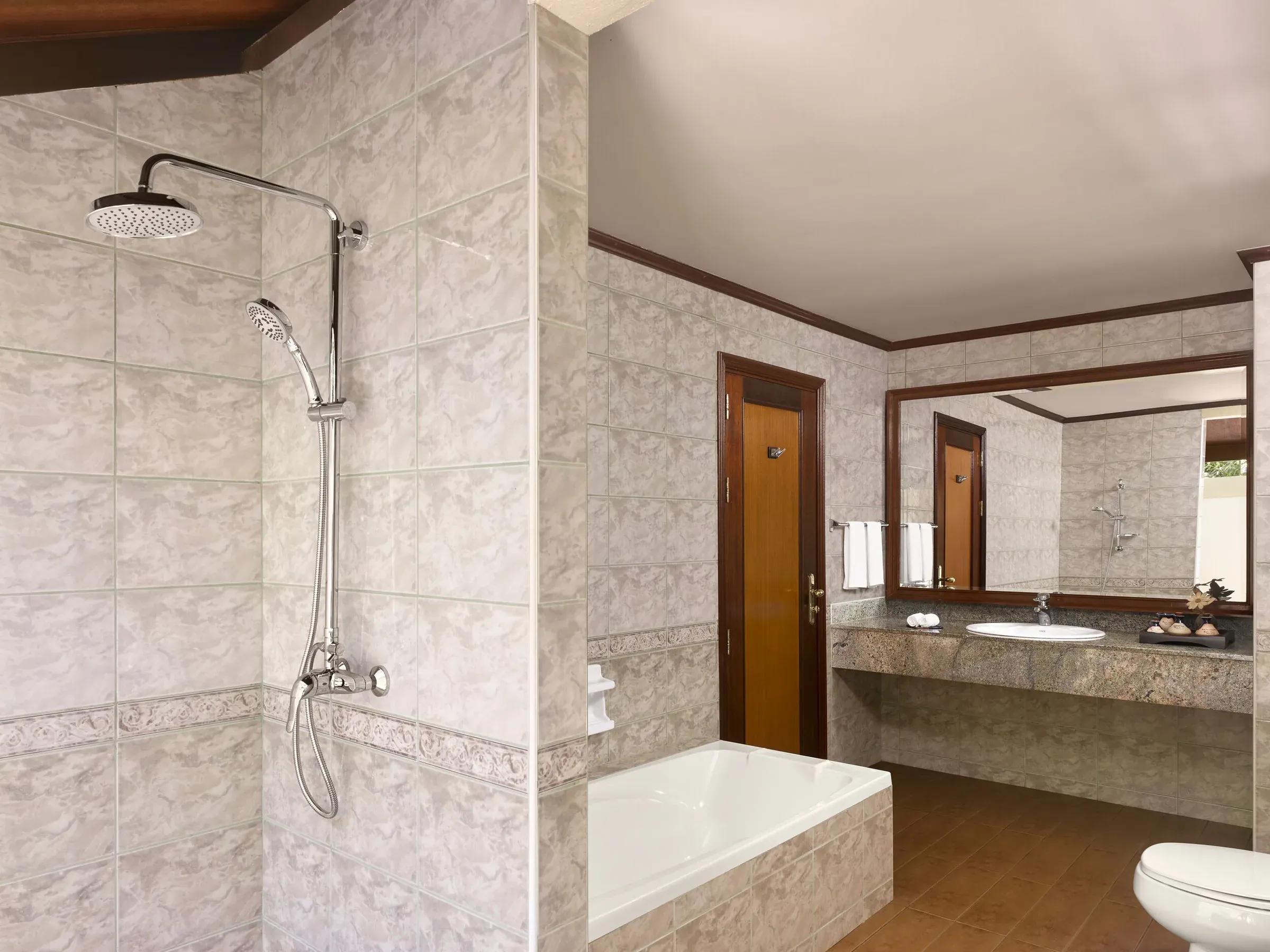 Spazioso bagno della Beach Villa con doccia a pioggia, vasca separata e ampio lavabo con ripiano in granito, un'oasi di relax al Royal Island Resort & Spa.