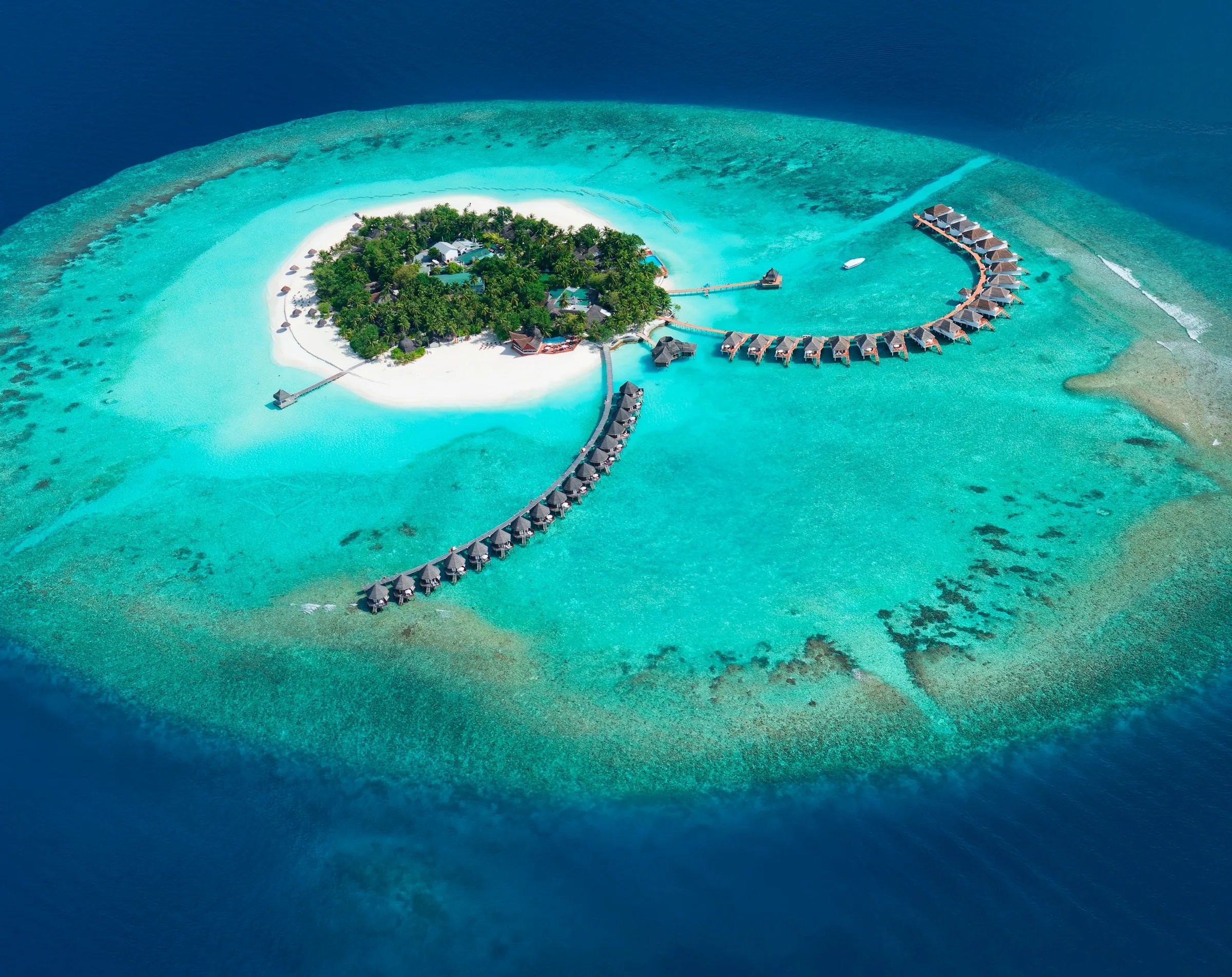 Veduta aerea del Thulhagiri Island Resort & Spa con bungalow sull'acqua e spiaggia bianca.