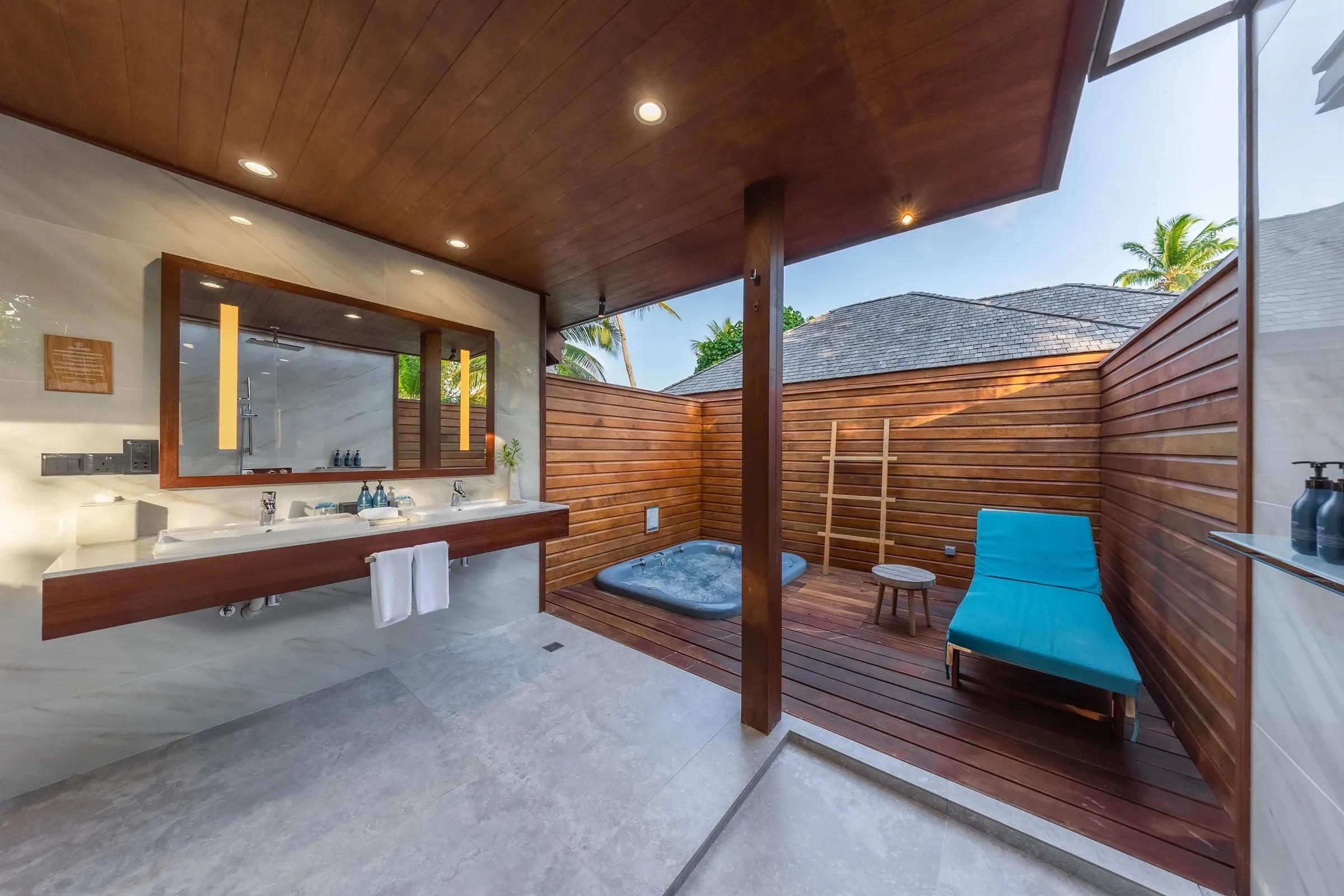 Bagno con doppio lavabo e area esterna con vasca idromassaggio nella Beach Villa del Veligandu Island Resort & Spa.