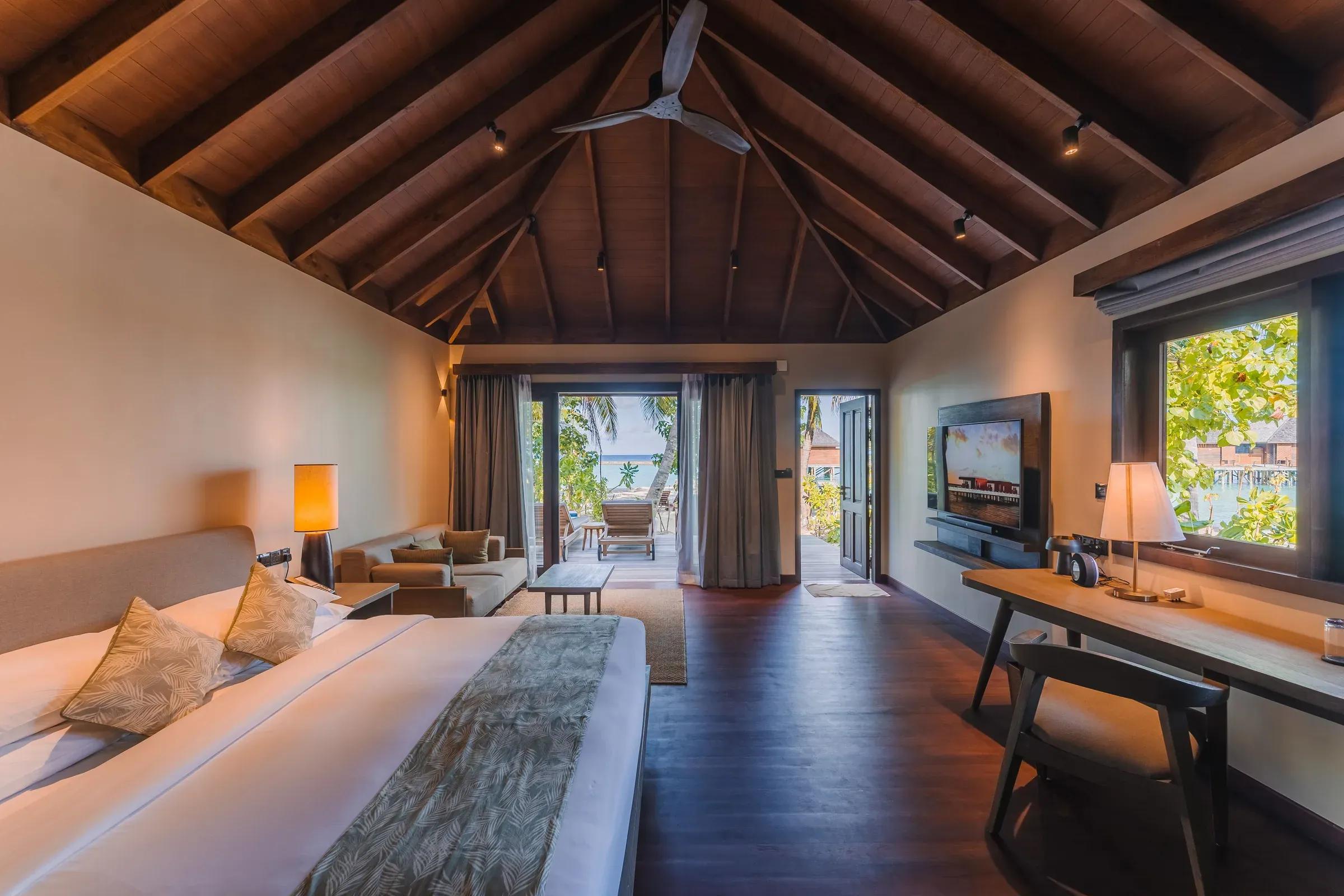 Interno della Beach Villa con letto king-size e terrazza vista mare al Veligandu Island Resort & Spa.