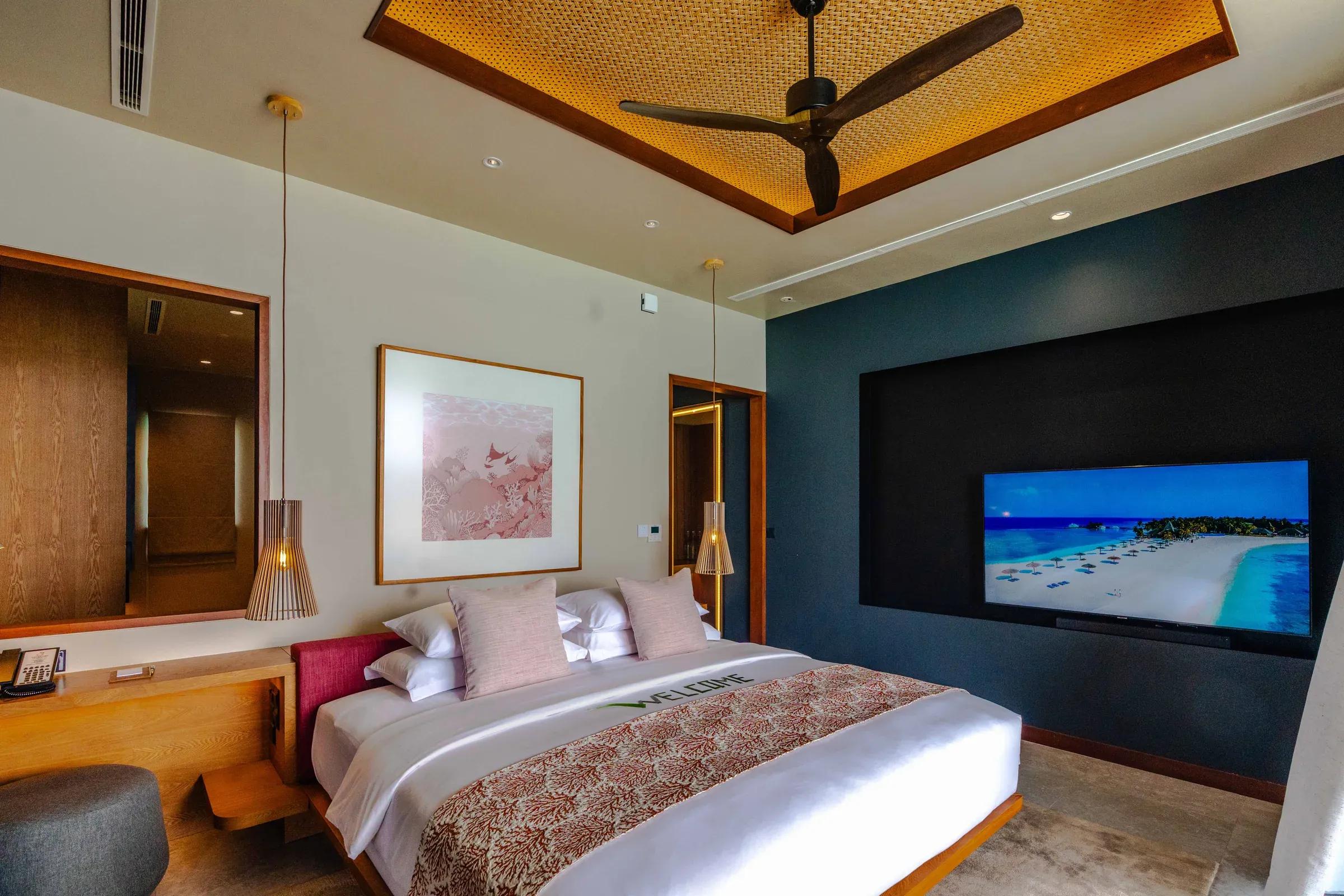 Camera da letto con letto matrimoniale e televisore nell'Ocean Pool Villa del Veligandu Island Resort & Spa.