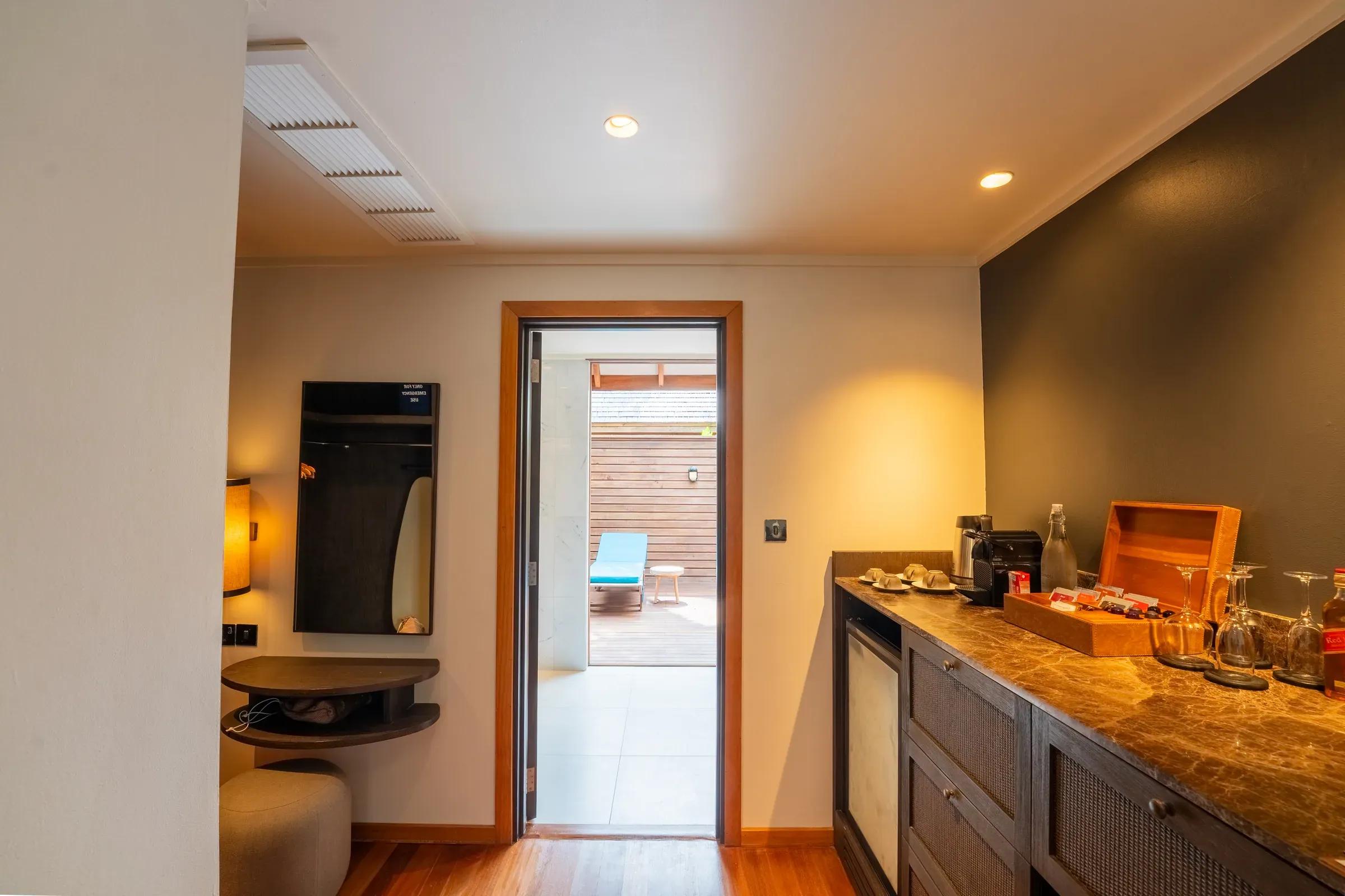 Interno della Sunset Jacuzzi Beach Villa con minibar e accesso alla terrazza con lettino al Veligandu Island Resort & Spa.