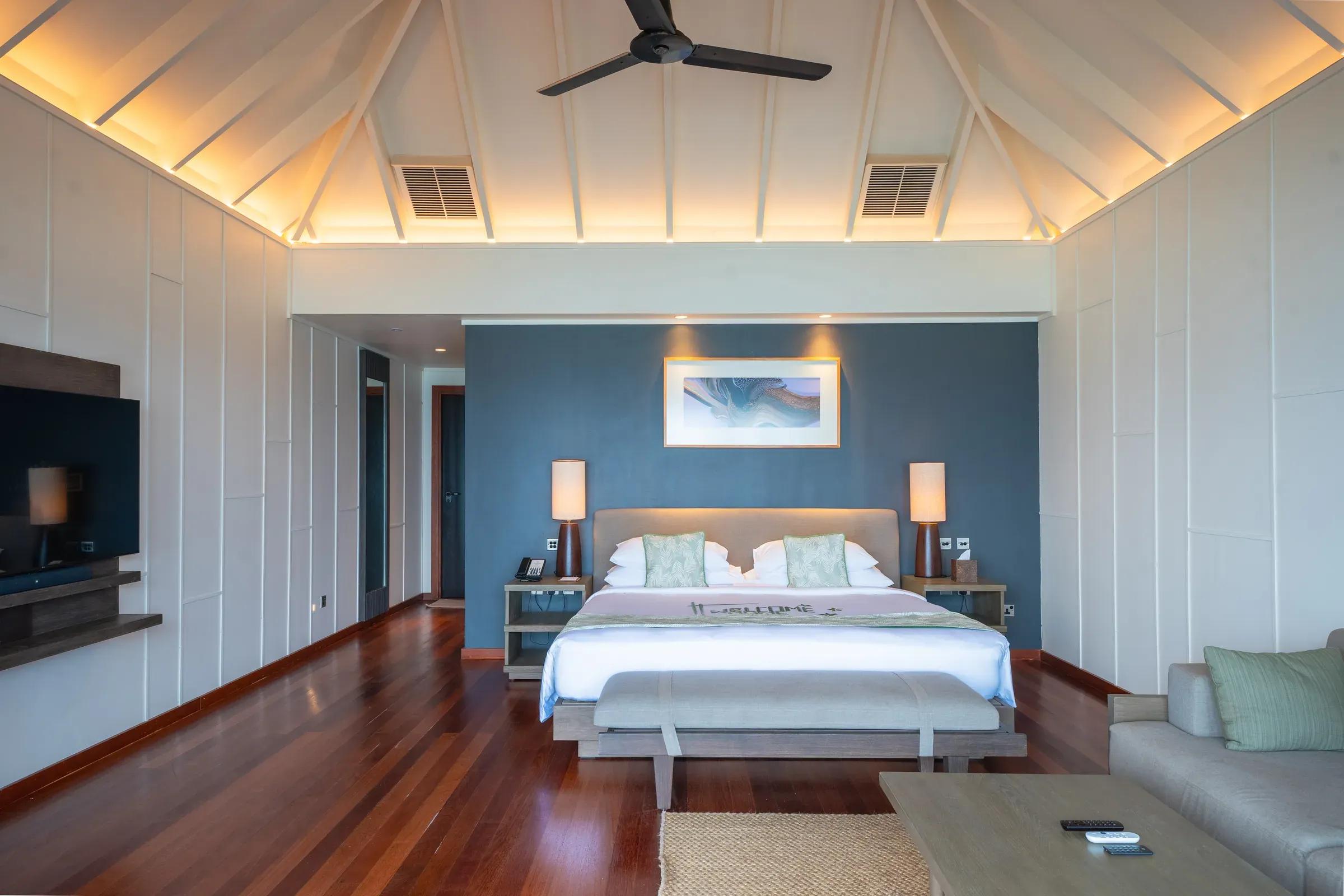 Camera da letto della Sunset Jacuzzi Beach Villa con letto matrimoniale e pavimento in legno al Veligandu Island Resort & Spa.