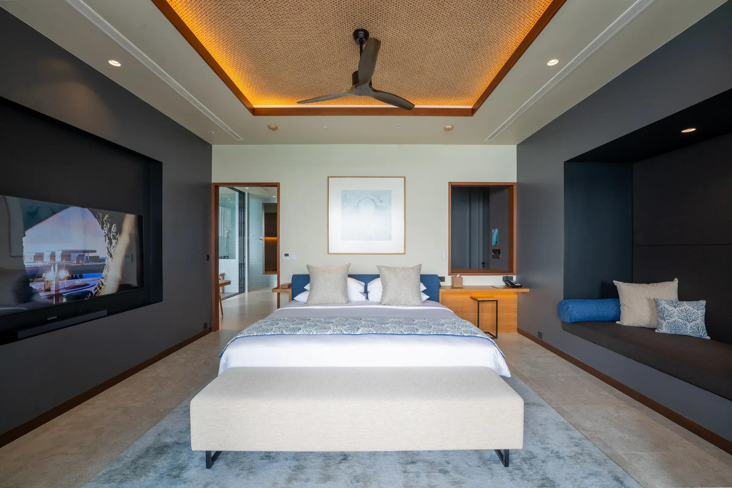 Interno della Sunset Ocean Pool Villa con letto matrimoniale, TV a schermo piatto e divano al Veligandu Island Resort & Spa.