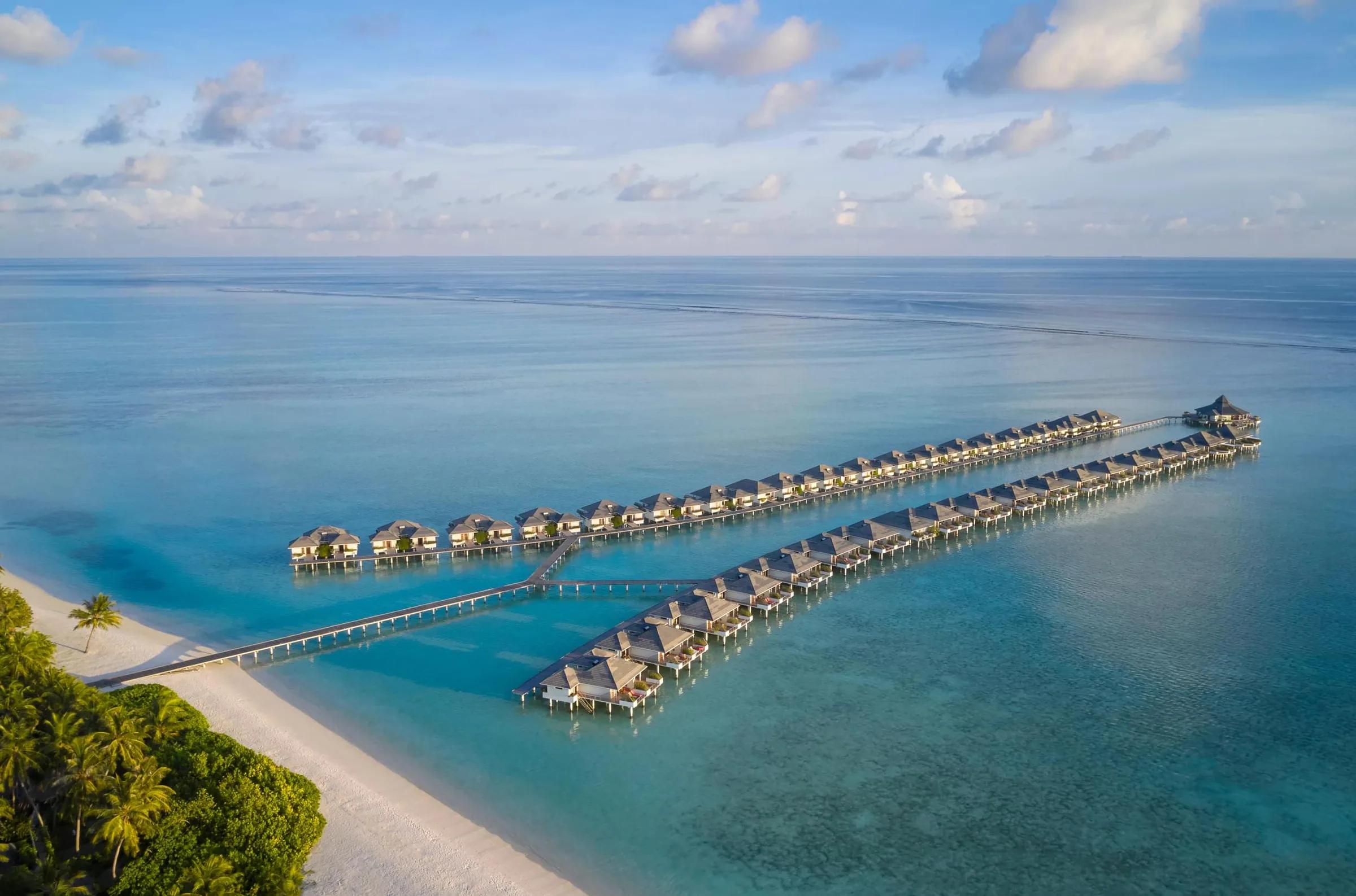 Spettacolare vista aerea delle iconiche ville sull'acqua del Villa Park Sun Island Resort & Spa, immerse nella laguna turchese cristallina delle Maldive.
